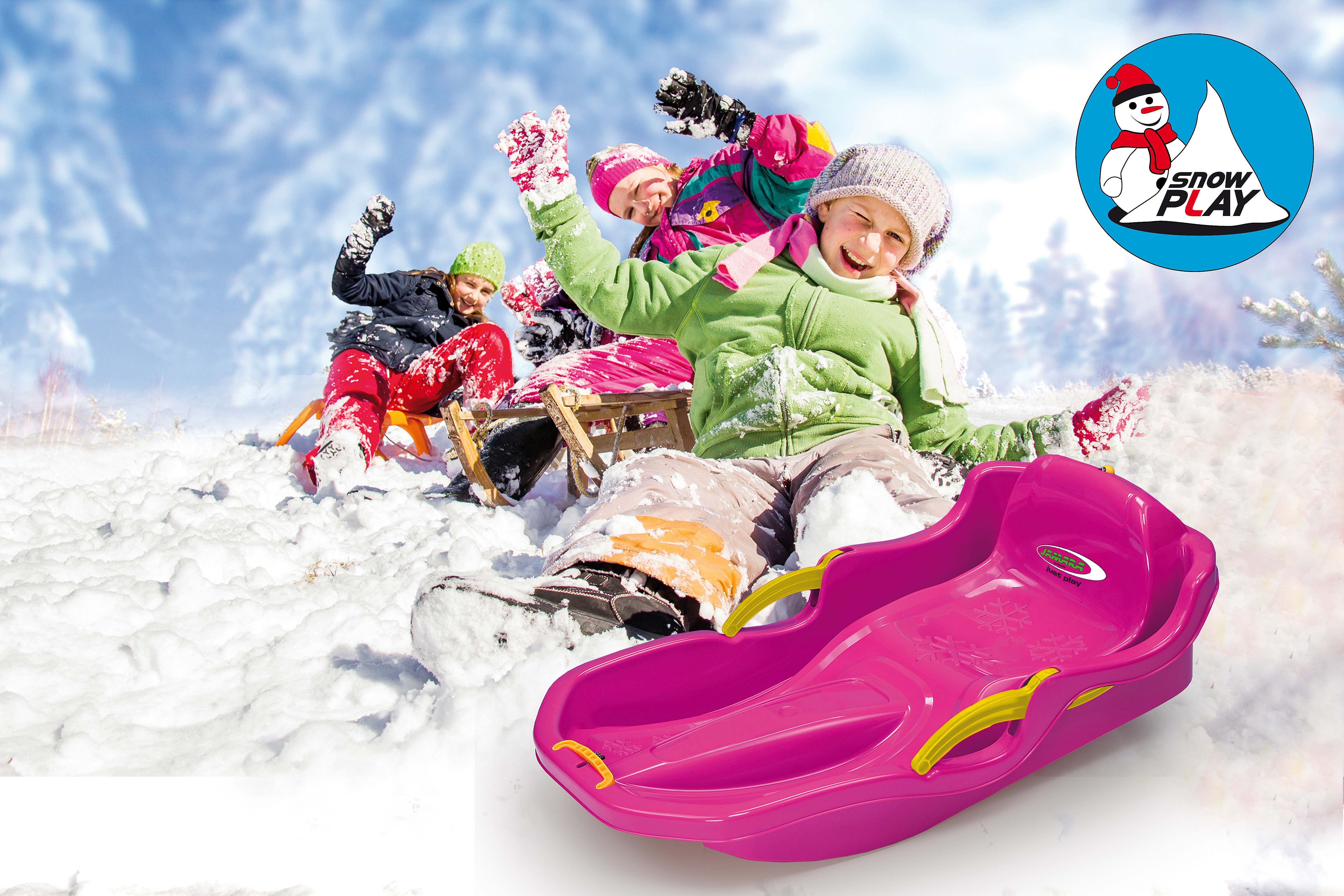Dzieci bawią się na śniegu z sankami. Różowe sanki na pierwszym planie. Ośnieżone drzewa w tle.