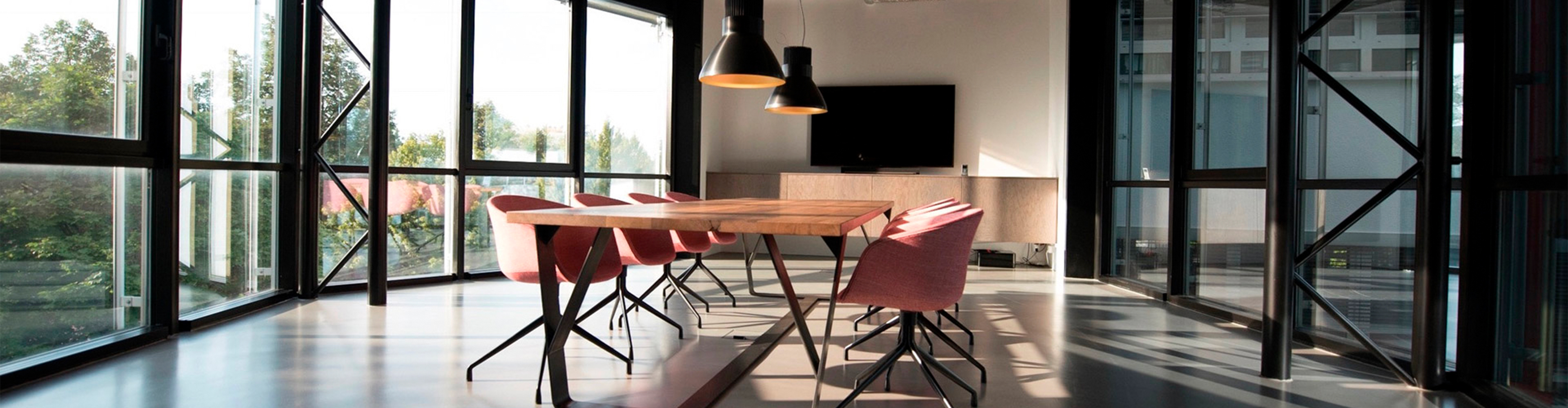 Nowoczesna jadalnia ze stołem z drewna i różowymi krzesłami. Duże okna oferują widok na drzewa i błyszczącą podłogę.