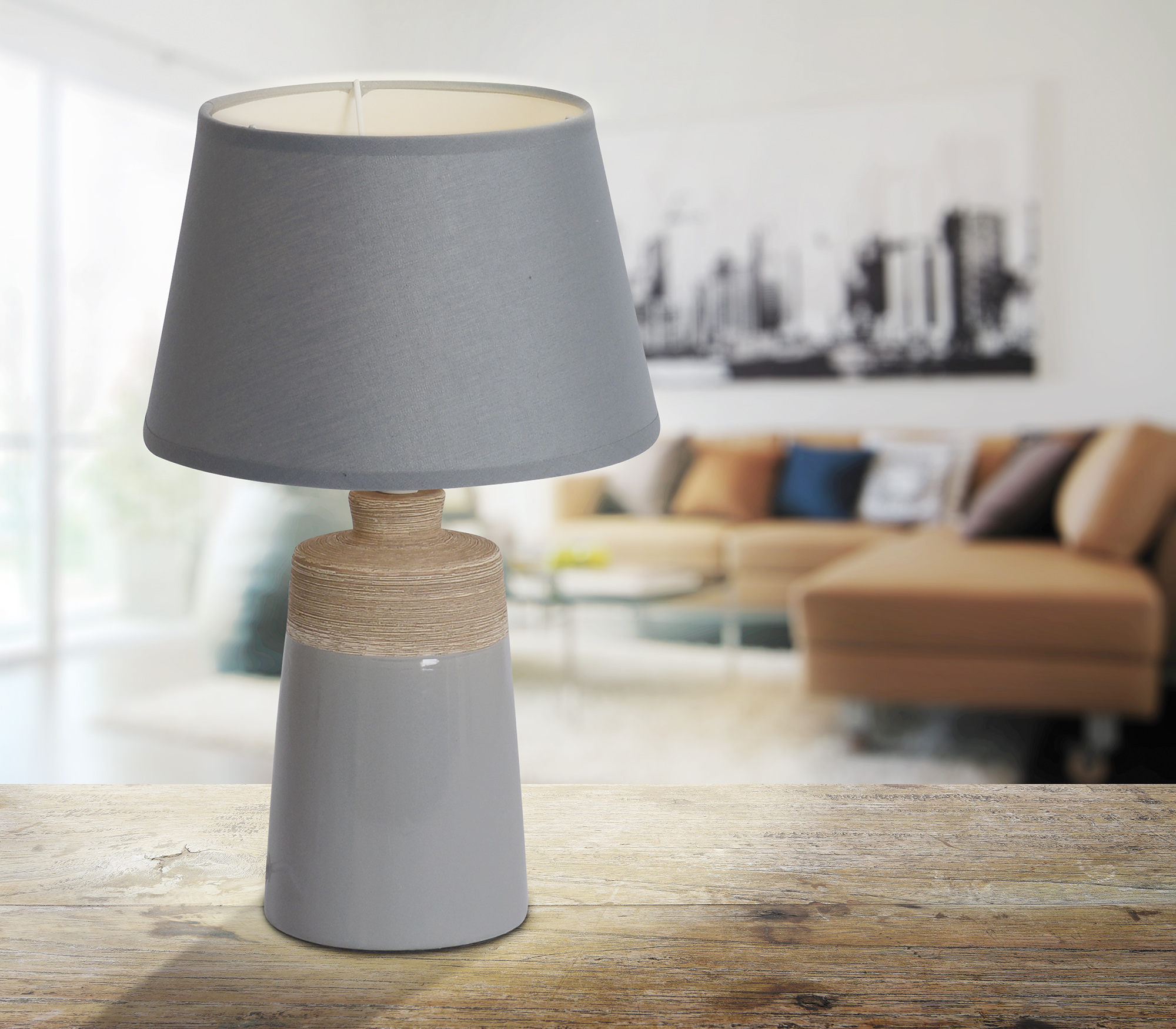 Graue Tischlampe mit Lampenschirm auf Holzoberfläche. Verschwommenes Wohnzimmer im Hintergrund.