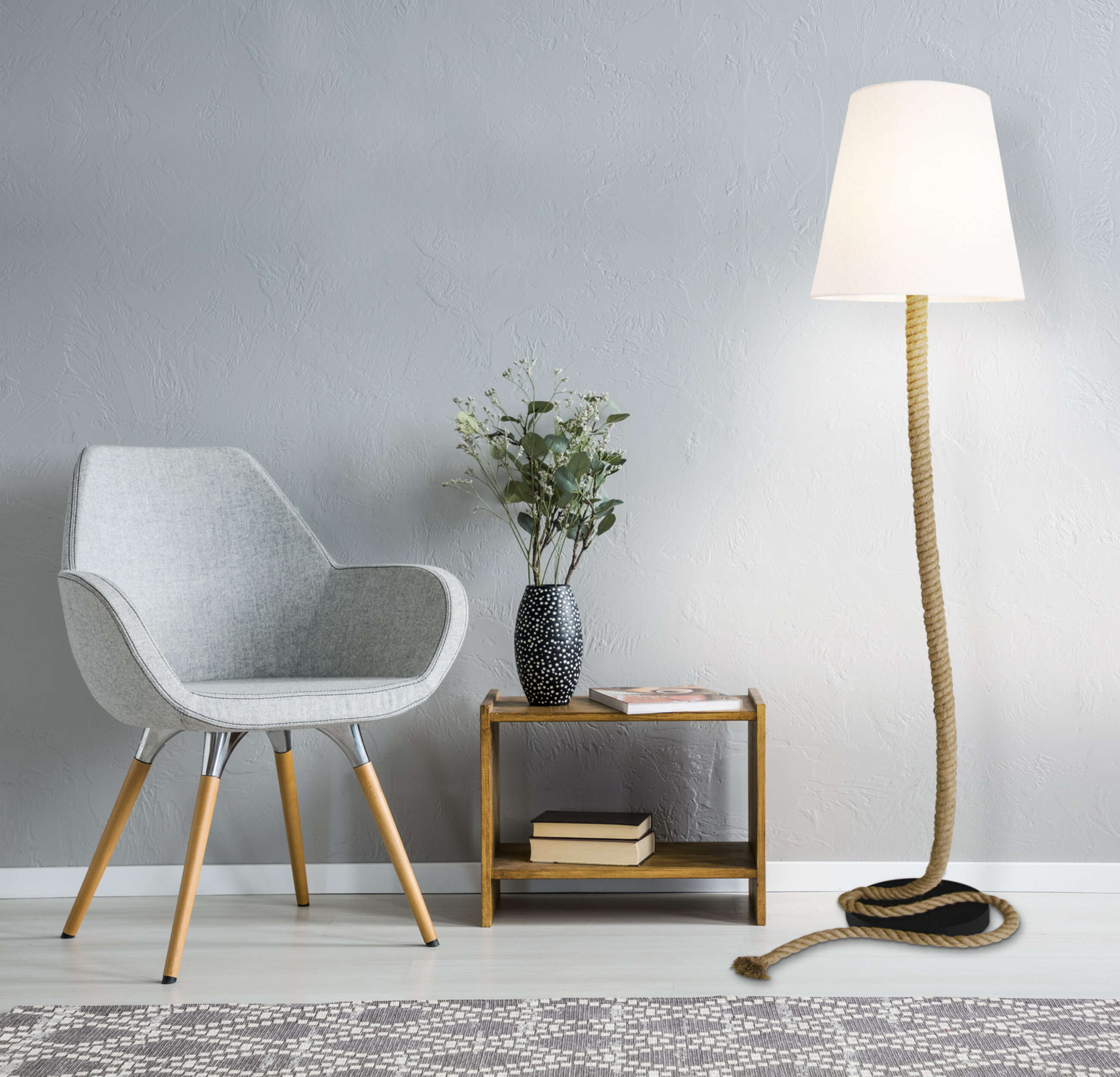 Zimmerinterieur mit grauem Stuhl, Holztisch mit Vase, Büchern und einer Seillampe.