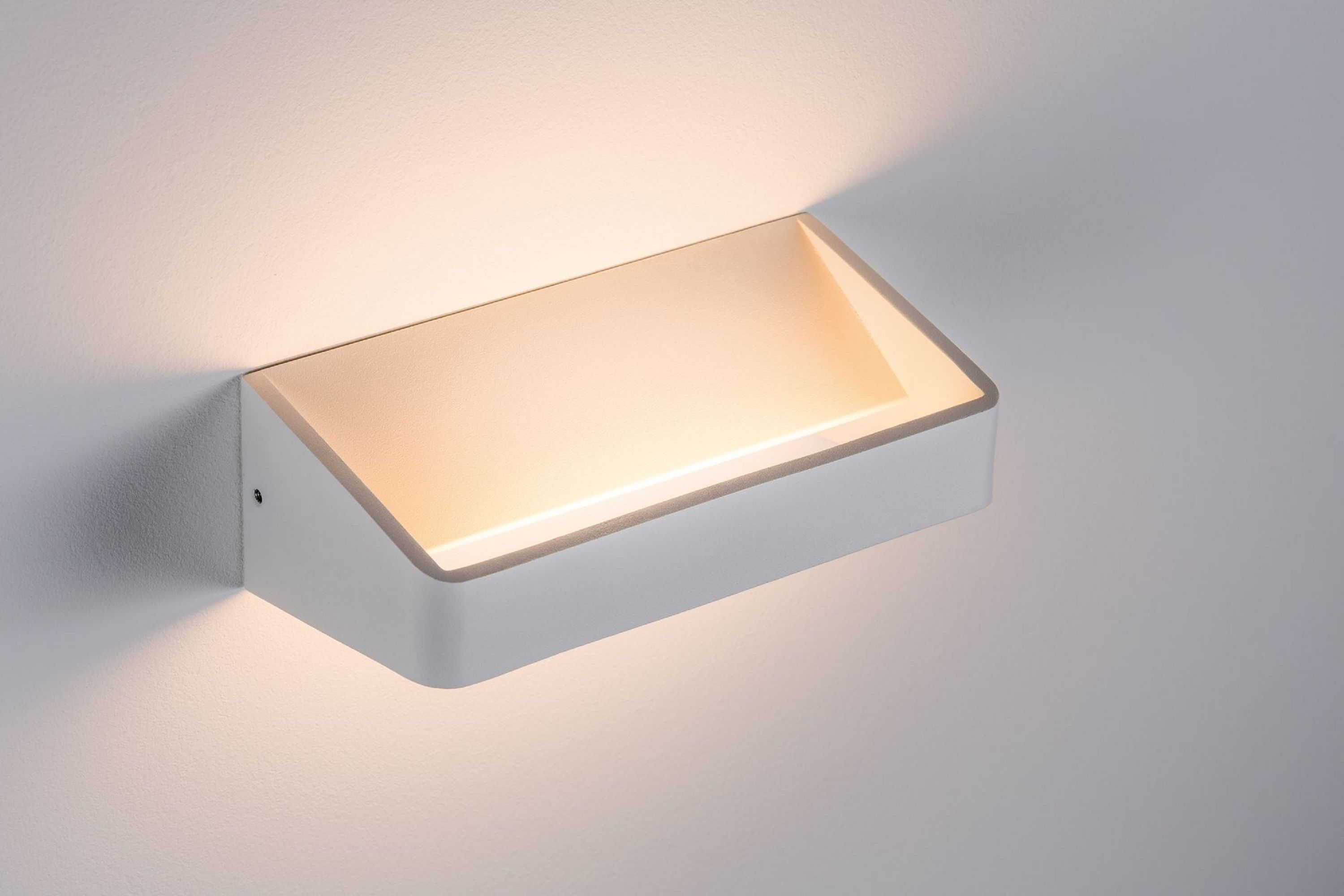 Eine weiße, rechteckige Wandleuchte mit Lichtquelle. Das Licht scheint auf die weiße Wand. Die Lampe ist an der Wand montiert.