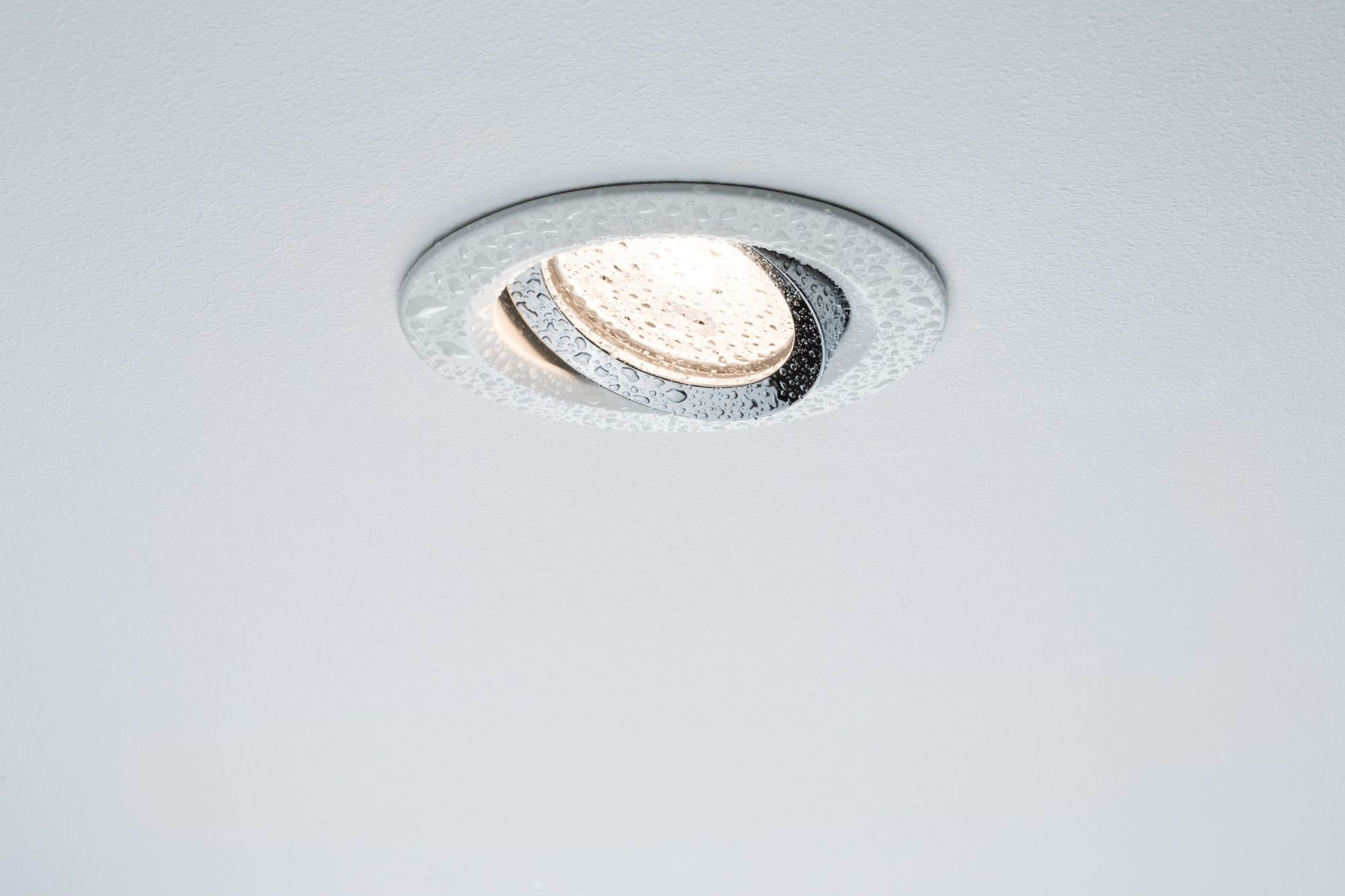 Eine Deckenleuchte mit Wassertropfen ist an einer weißen Decke montiert.