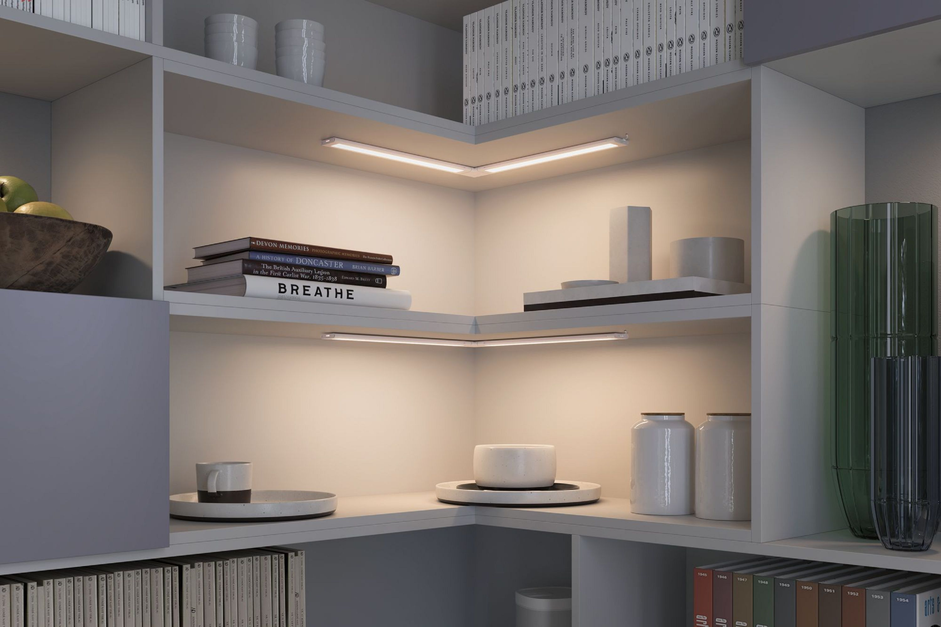 Un'unità a scaffali ben illuminata mostra libri, tazze, barattoli e vasi. Luci lineari illuminano i ripiani.