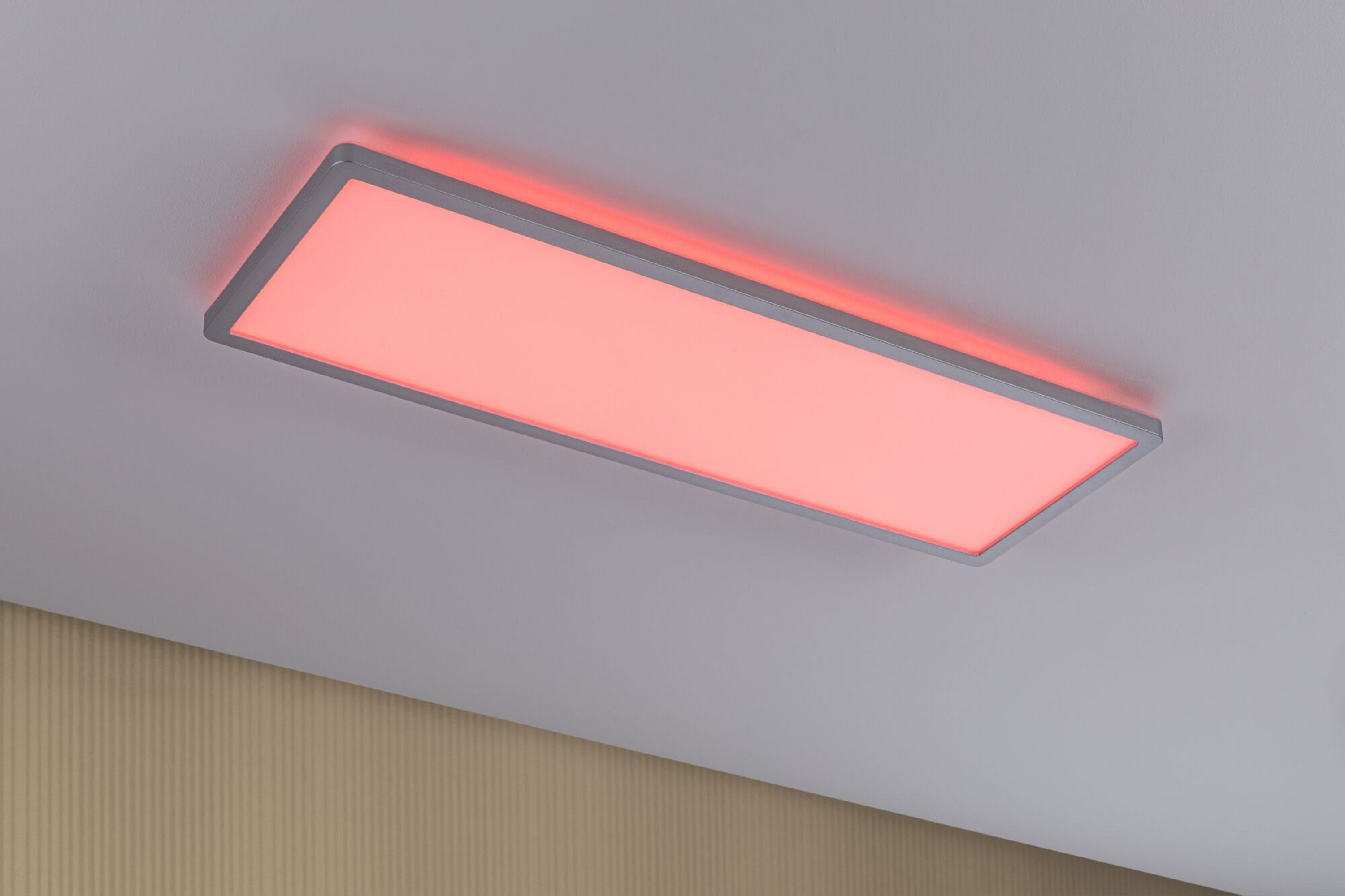 Eine rechteckige Deckenleuchte ist installiert. Sie hat einen silbernen Rahmen und strahlt rotes Licht aus. Der Hintergrund zeigt eine weiße Decke.