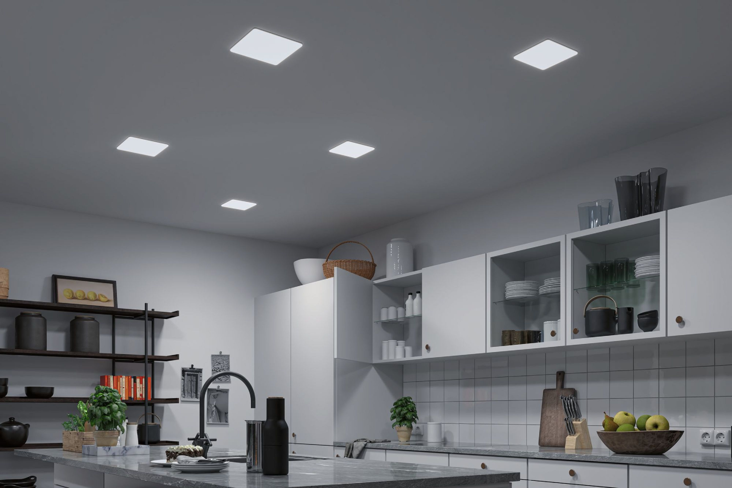 Una cucina moderna con luci a soffitto quadrate, armadi bianchi, un piano di lavoro grigio e vari utensili da cucina.