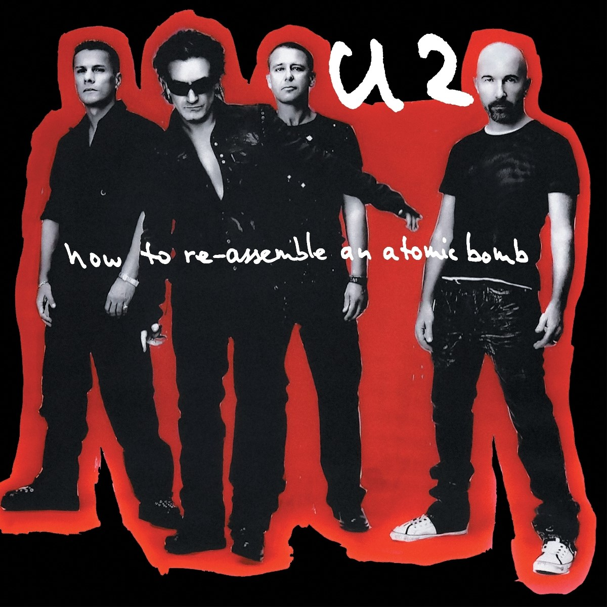 Membri della band U2 in posa su sfondo rosso. Il testo recita: how to re-assemble an atomic bomb. Abbigliamento nero.