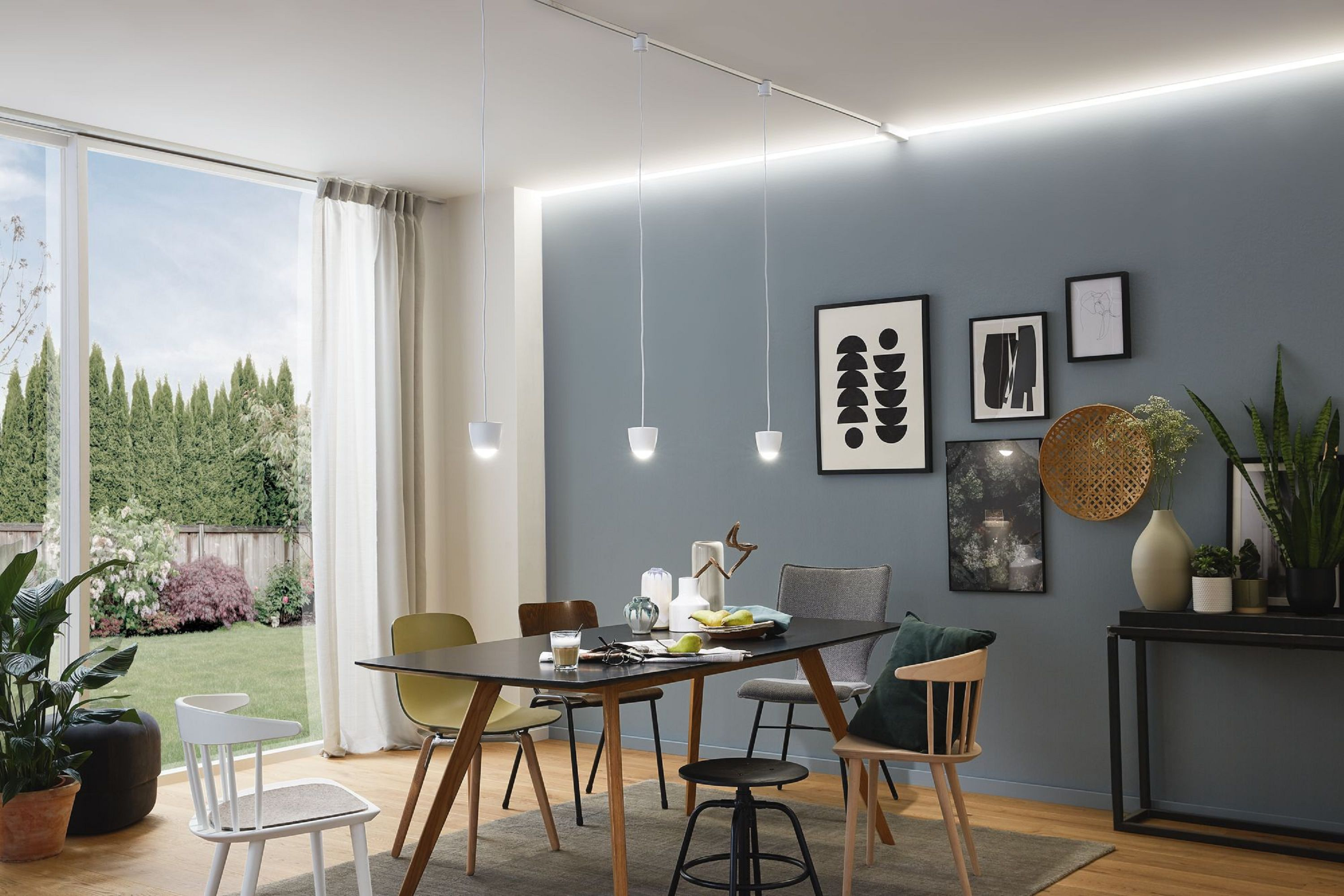 Jadalnia ze stołem, krzesłami, sztuką i dużym oknem z widokiem na ogród.