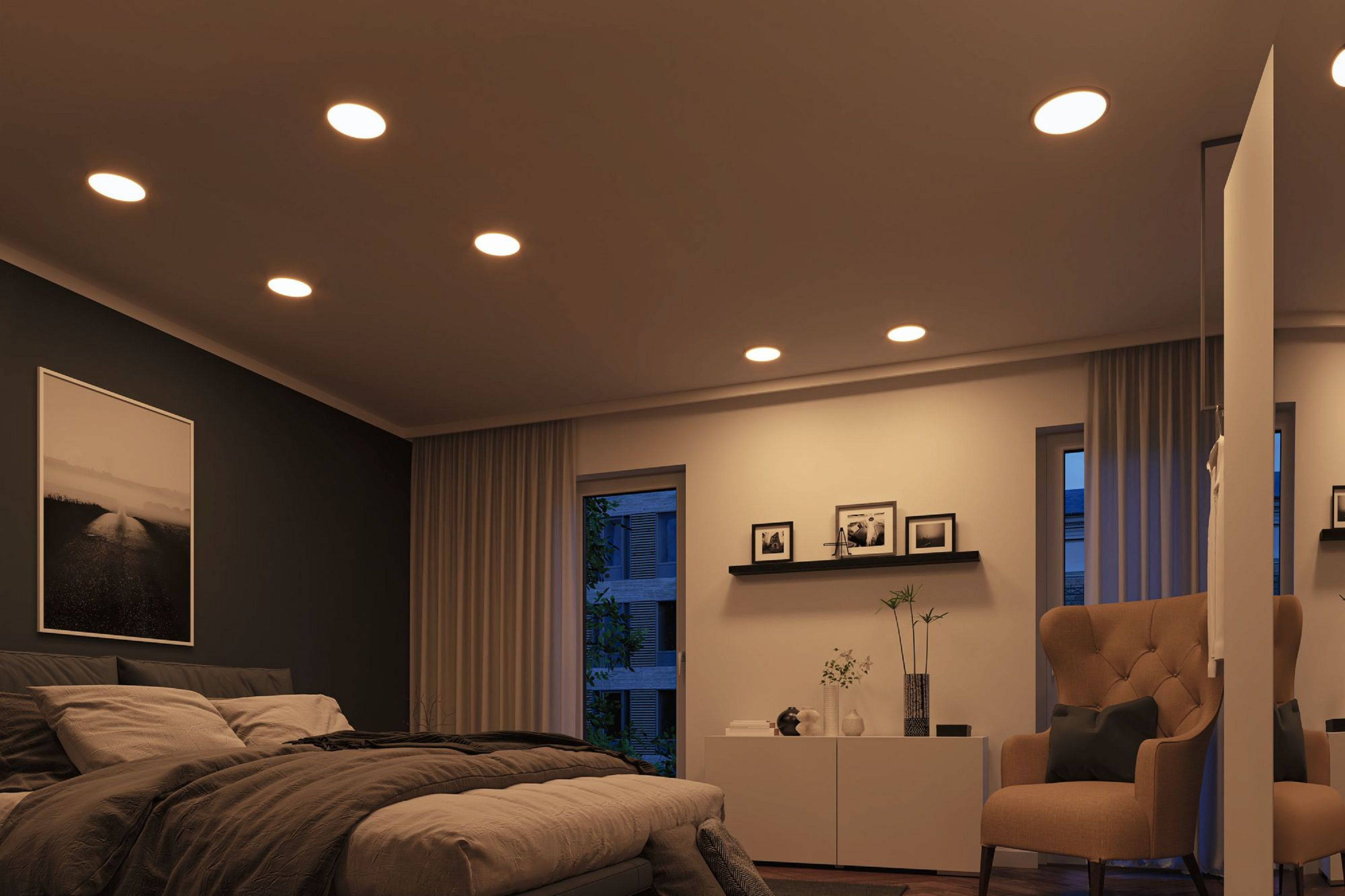 Schlafzimmer mit Bett, Sessel und Kunst. Einbaudeckenleuchten beleuchten den Raum. Fenster bieten einen Blick nach draußen.
