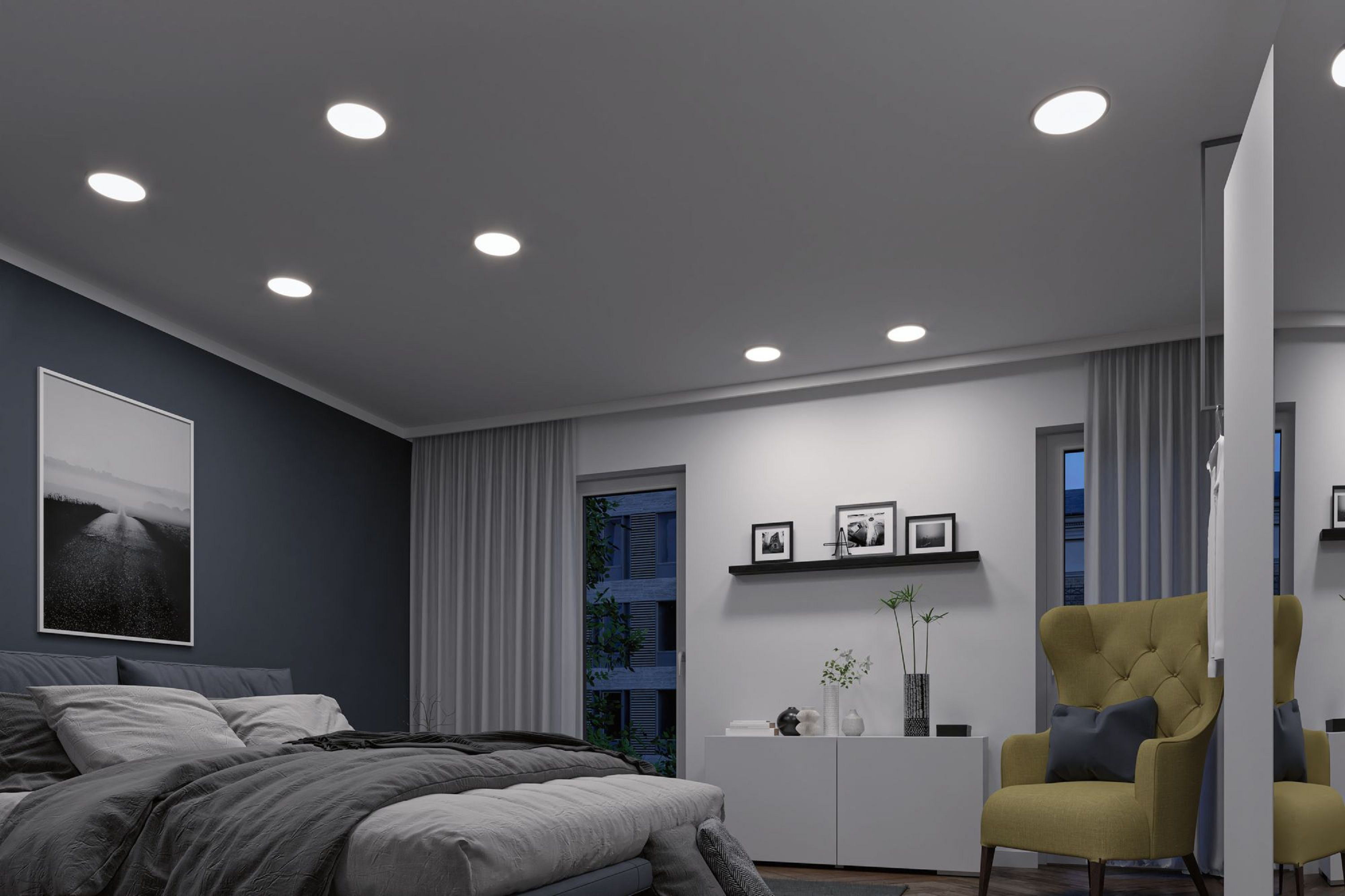 Ein Schlafzimmer mit Einbauleuchten, einem Bett, einem Bild, einem grünen Stuhl und einem Fenster.