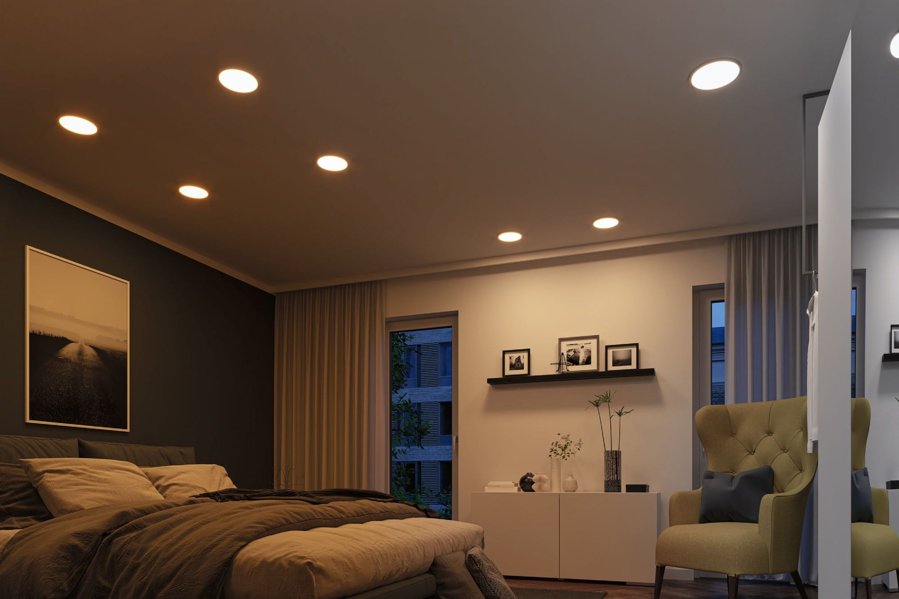 Schlafzimmer mit Bett, Sessel und Kunst. Lichter in der Decke. Fenster mit Vorhängen. Neutrale Töne und warme Beleuchtung.