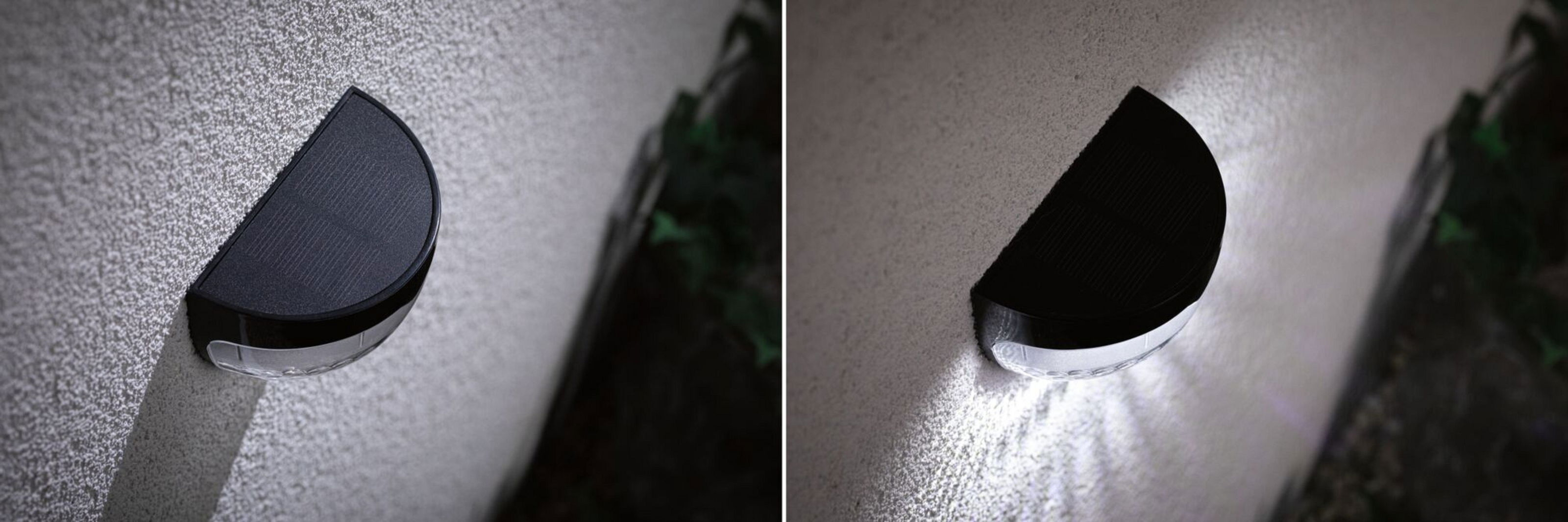 Eine schwarze, halbkreisförmige Solarlampe ist an einer strukturierten weißen Wand befestigt. Die Lampe beleuchtet die Wand.