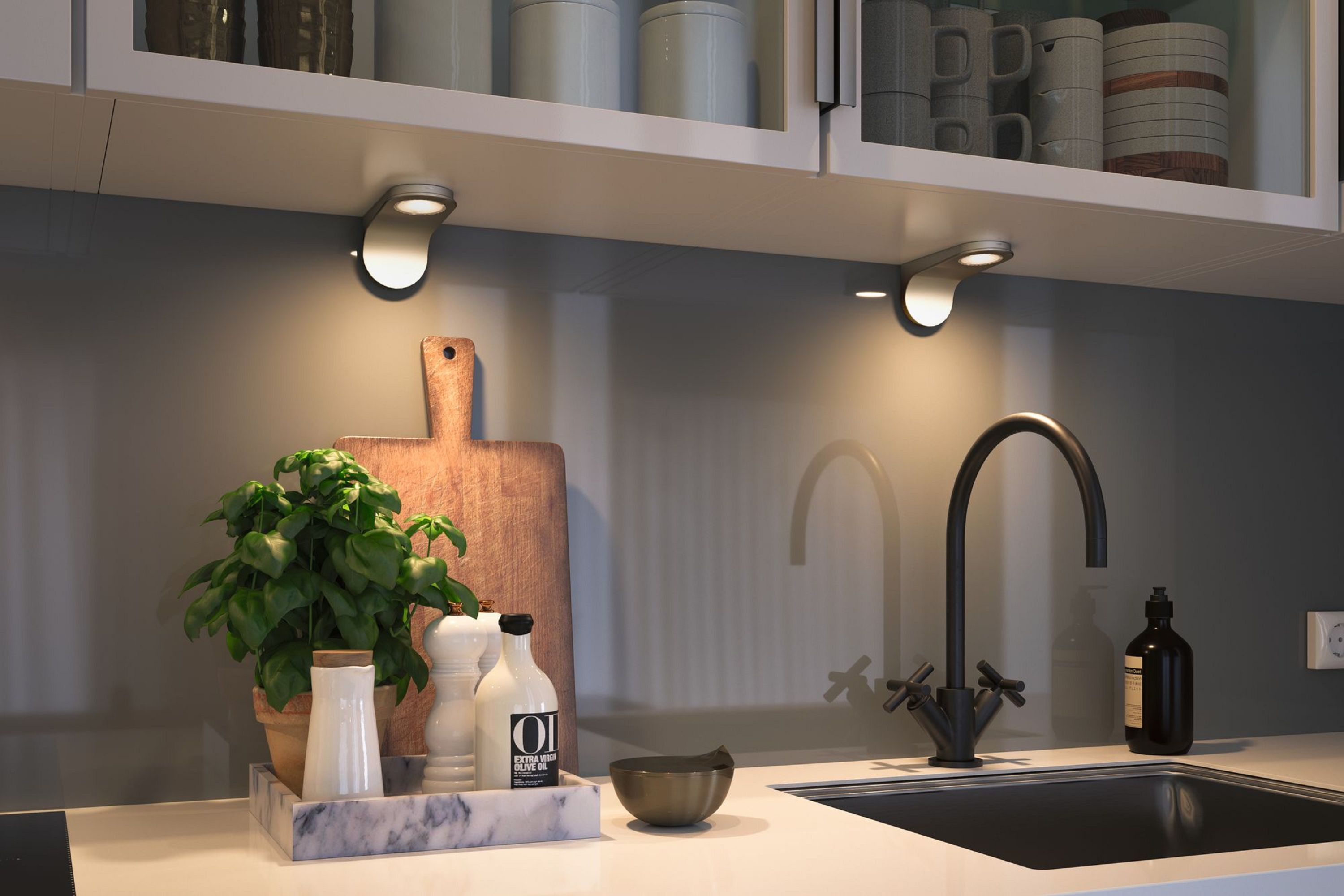 Scena di cucina con pianta, tagliere, lavandino e rubinetto. Le luci a soffitto illuminano l'area.