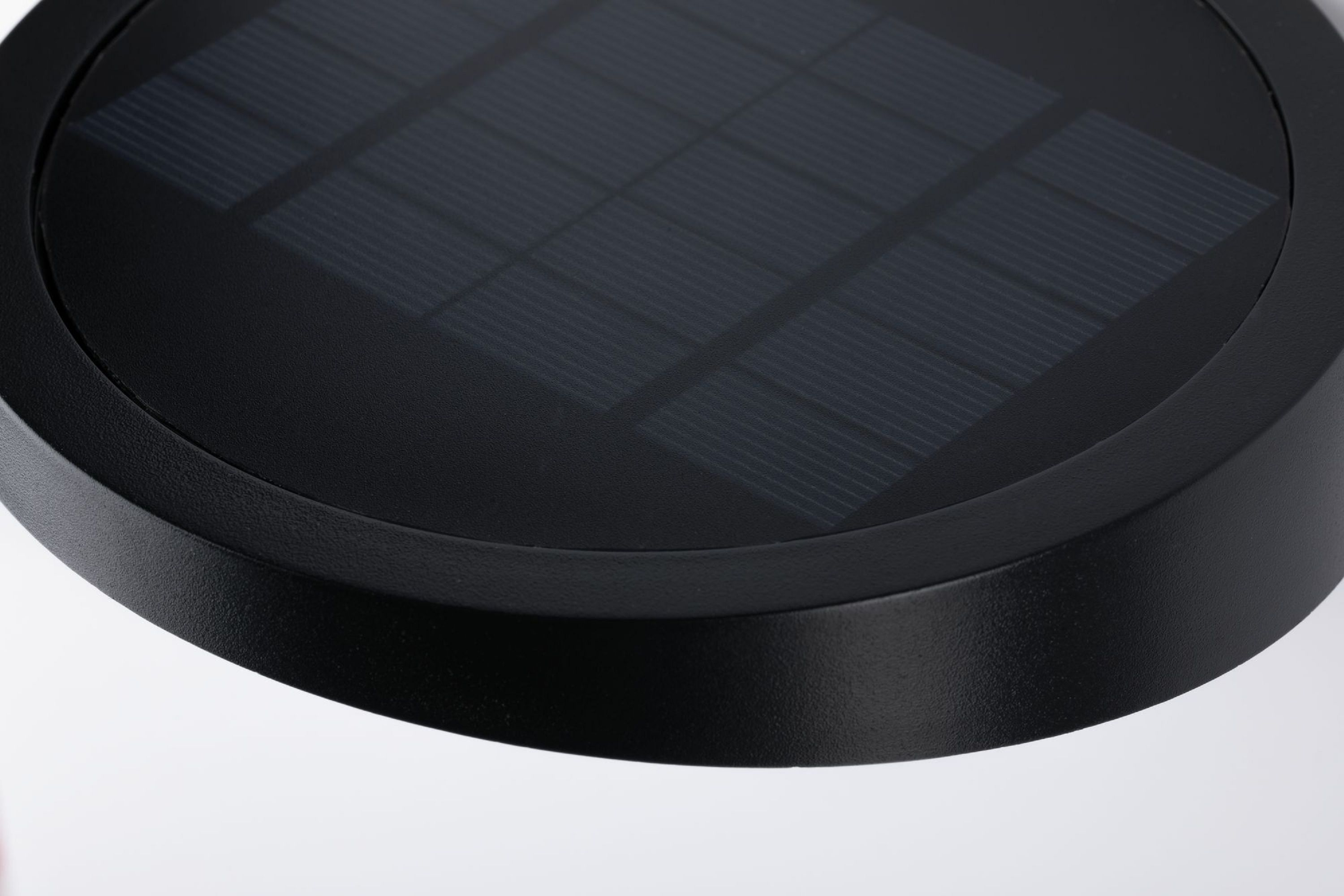 Zbliżenie czarnego panelu słonecznego z ciemną, teksturowaną powierzchnią na białym tle.