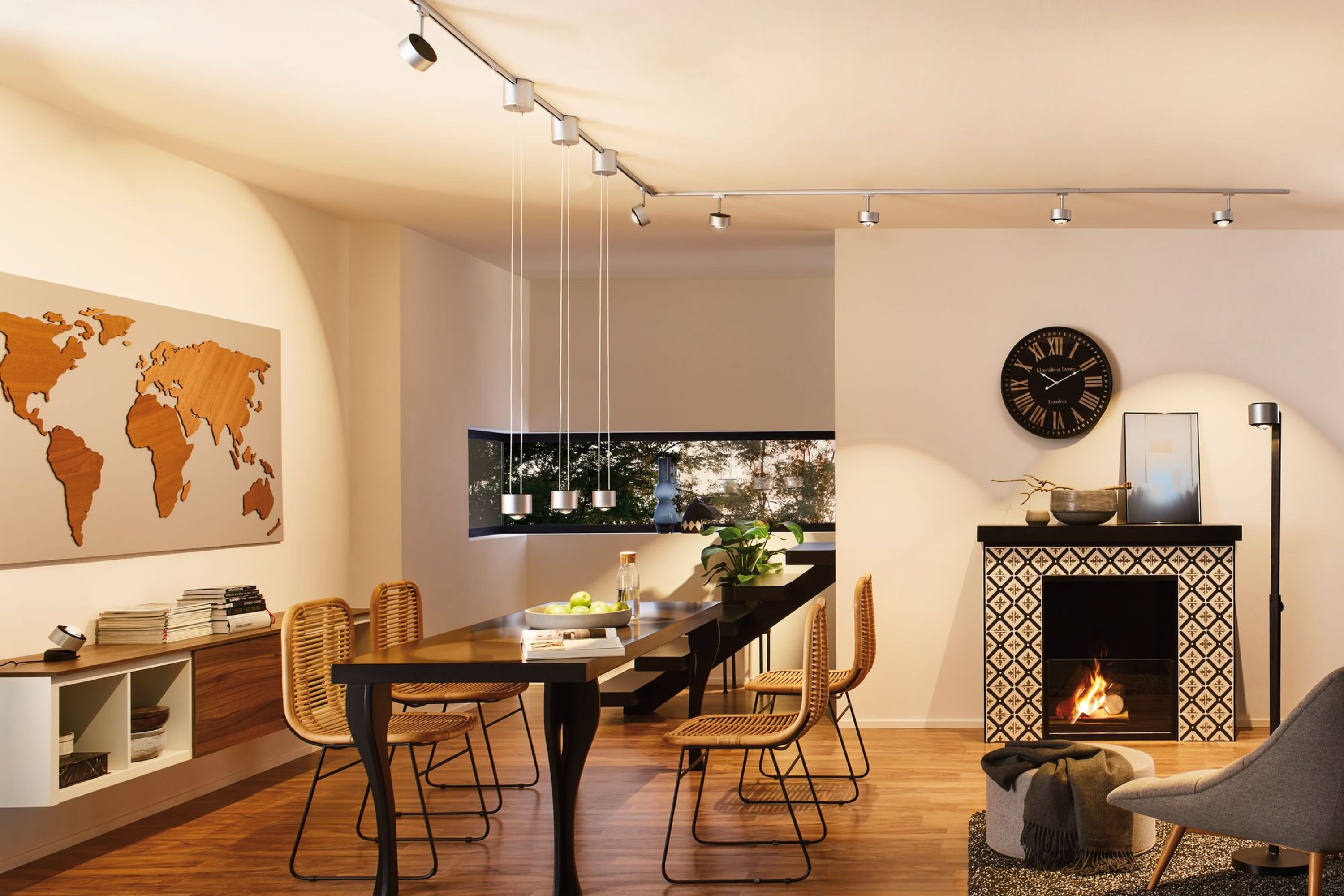 Wnętrze jadalni ze stołem, krzesłami, kominkiem i mapą świata na ścianie.