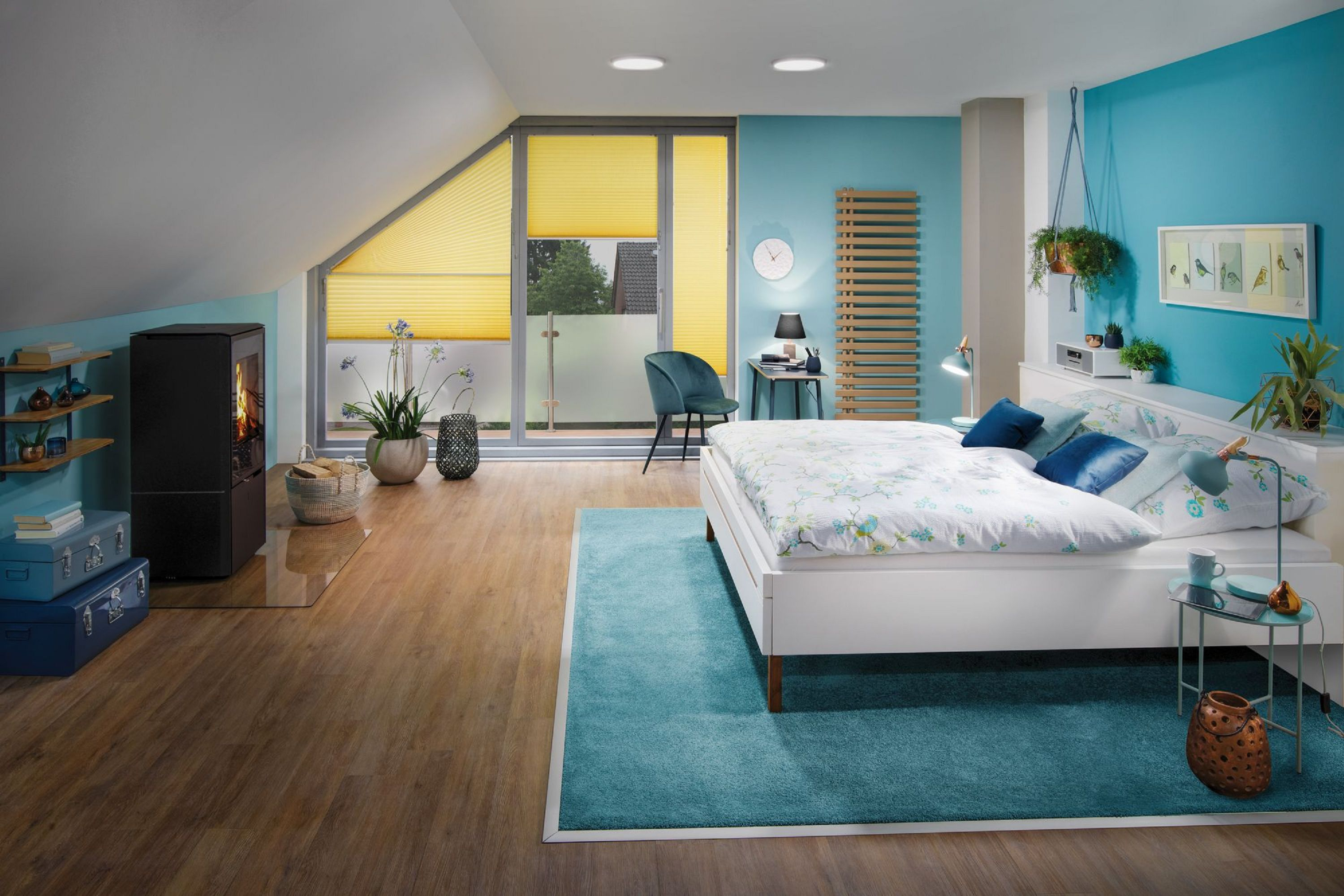 Camera da letto con letto, camino e tende gialle. Muri e tappeto blu. Piante e oggetti decorativi visibili.
