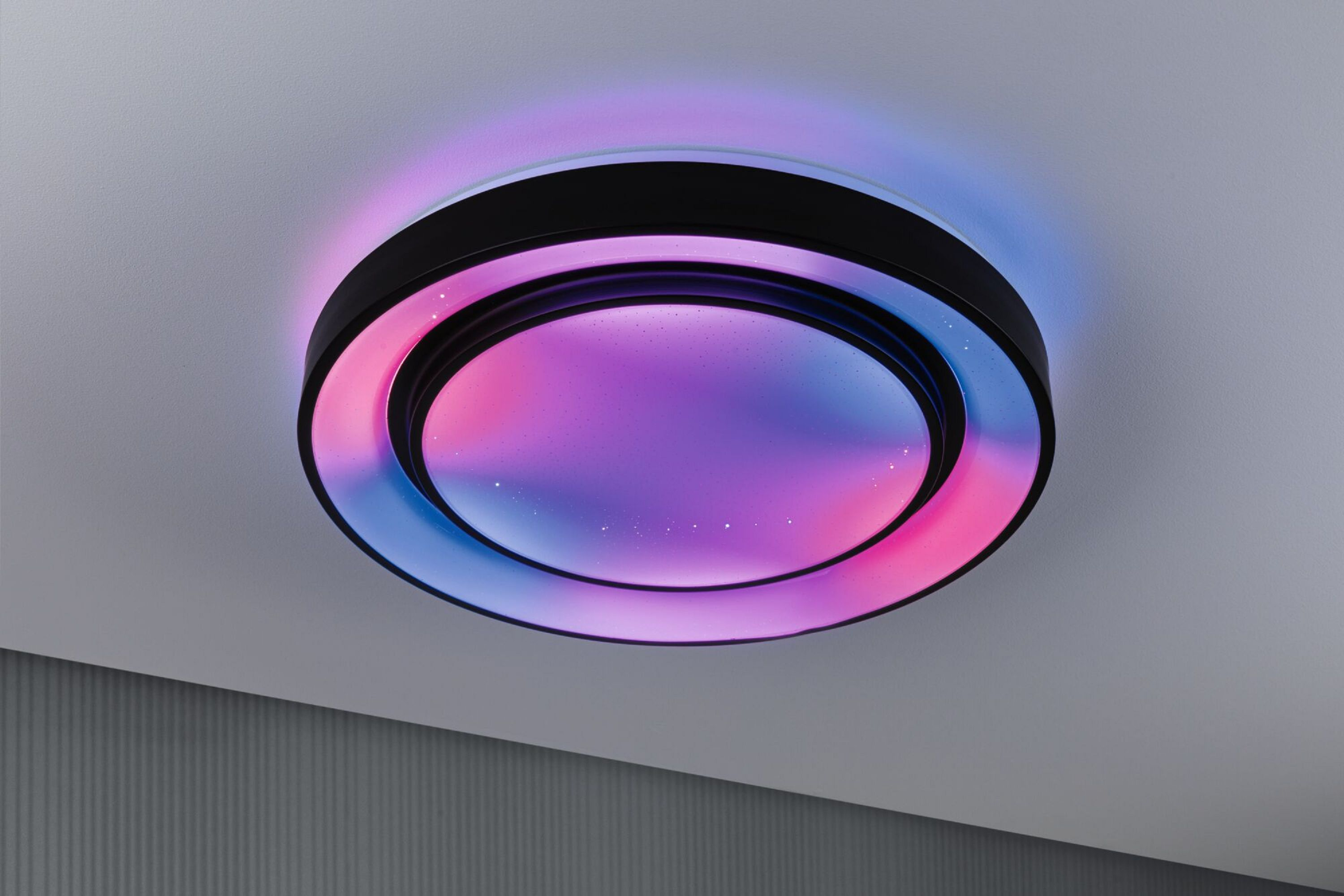 Una moderna plafoniera con cornice nera. Si illumina con luce rosa, viola e blu, creando un effetto vibrante.