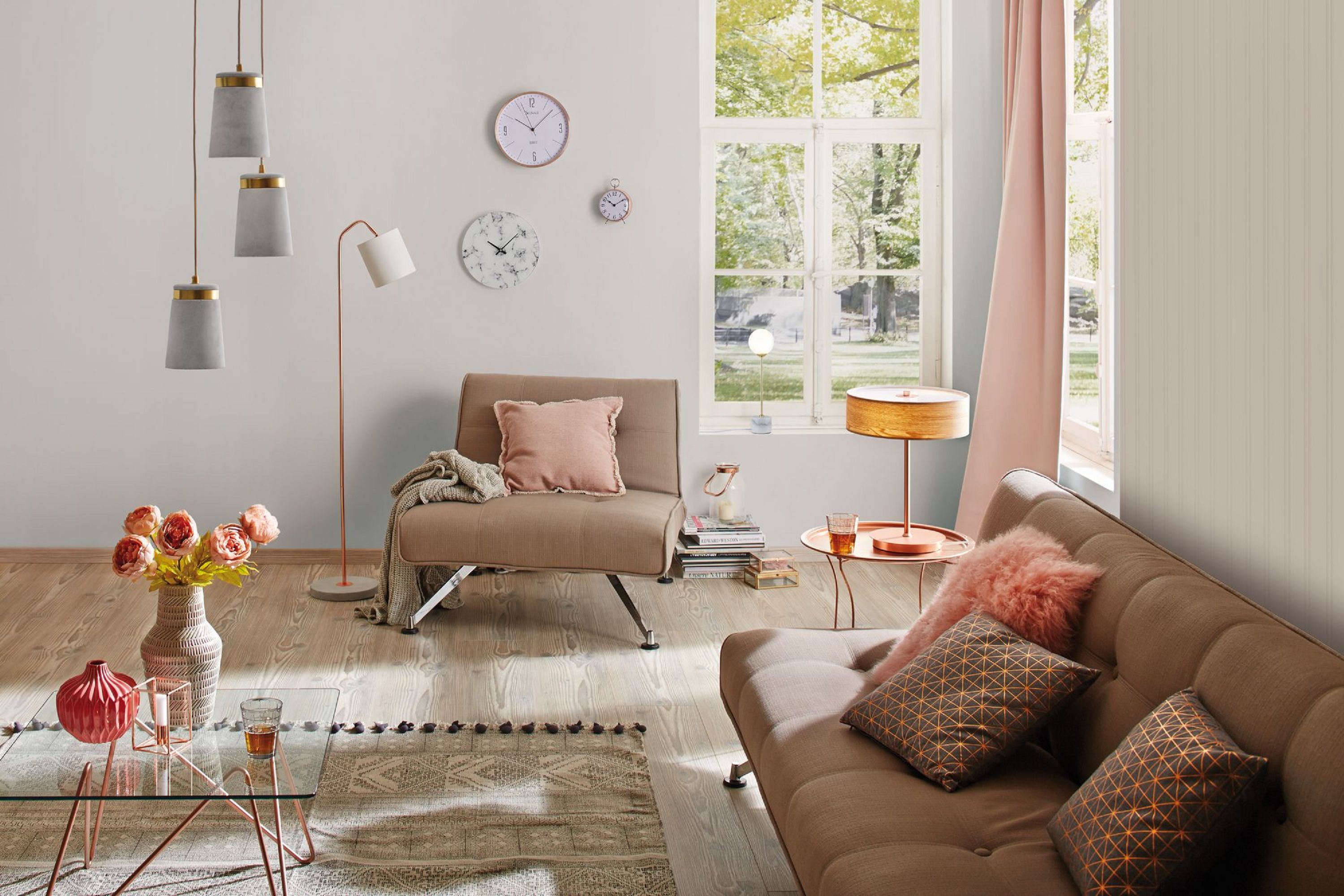Salon z sofą, krzesłem, lampami, kwiatami i zegarami. Okno odsłania widok na zieleń. Pokój jest beżowy i miękki.
