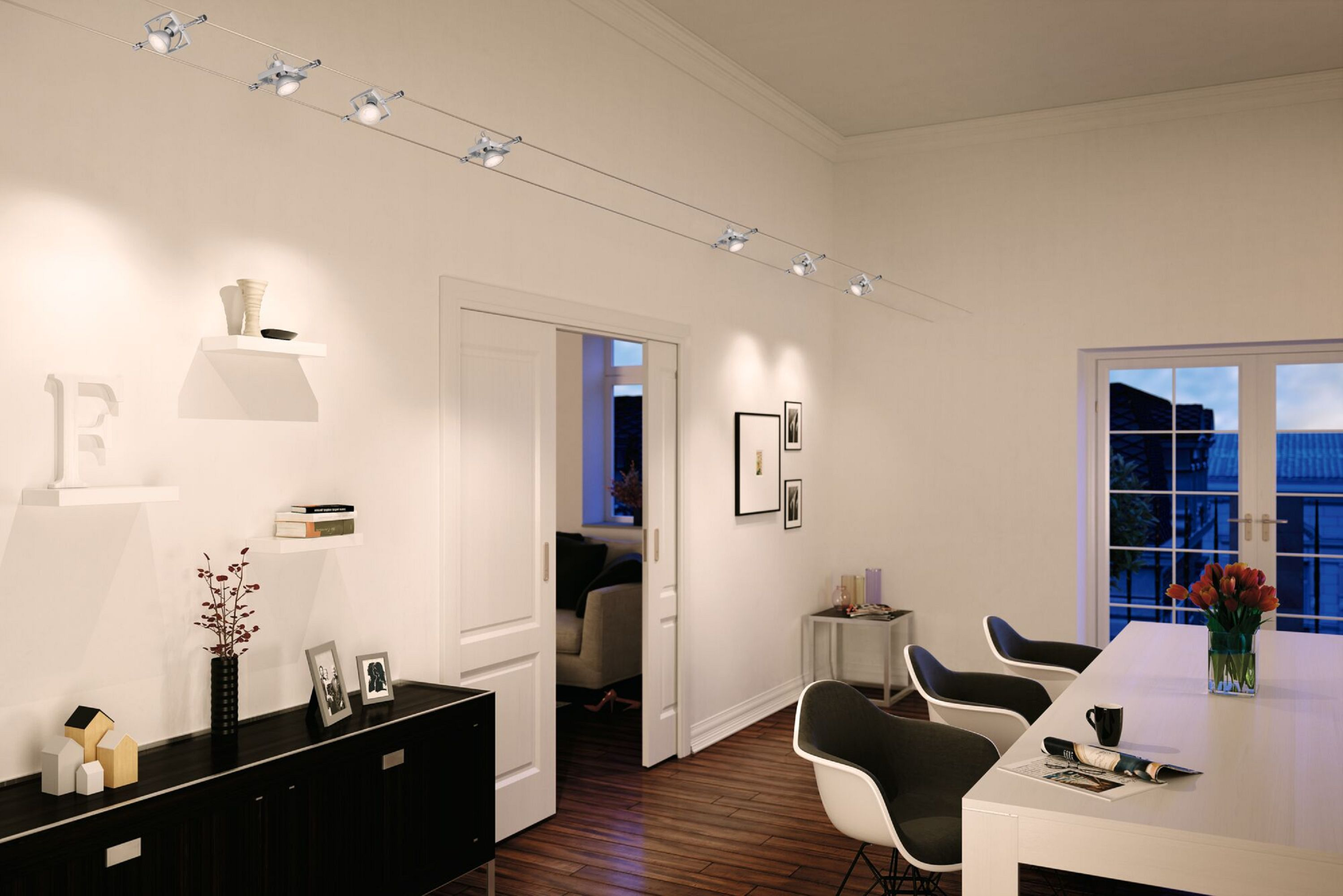 Nowoczesny salon z białymi ścianami, czarnymi meblami, oświetleniem szynowym i jadalnią ze stołami i krzesłami.