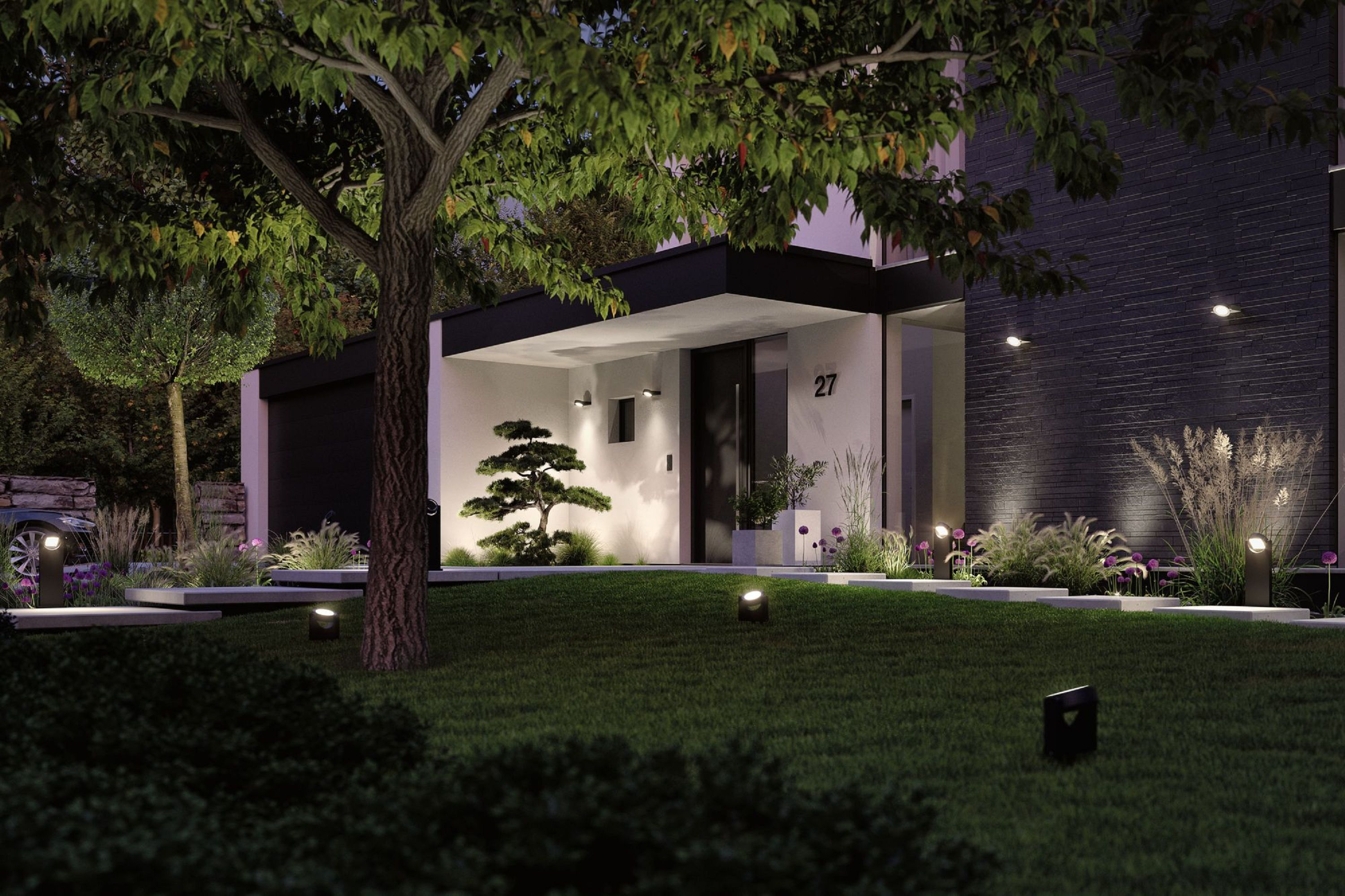 Nocna scena nowoczesnego domu z trawnikiem, drzewem i światłami. Numer domu 27. Zielona trawa i krzewy z przodu.