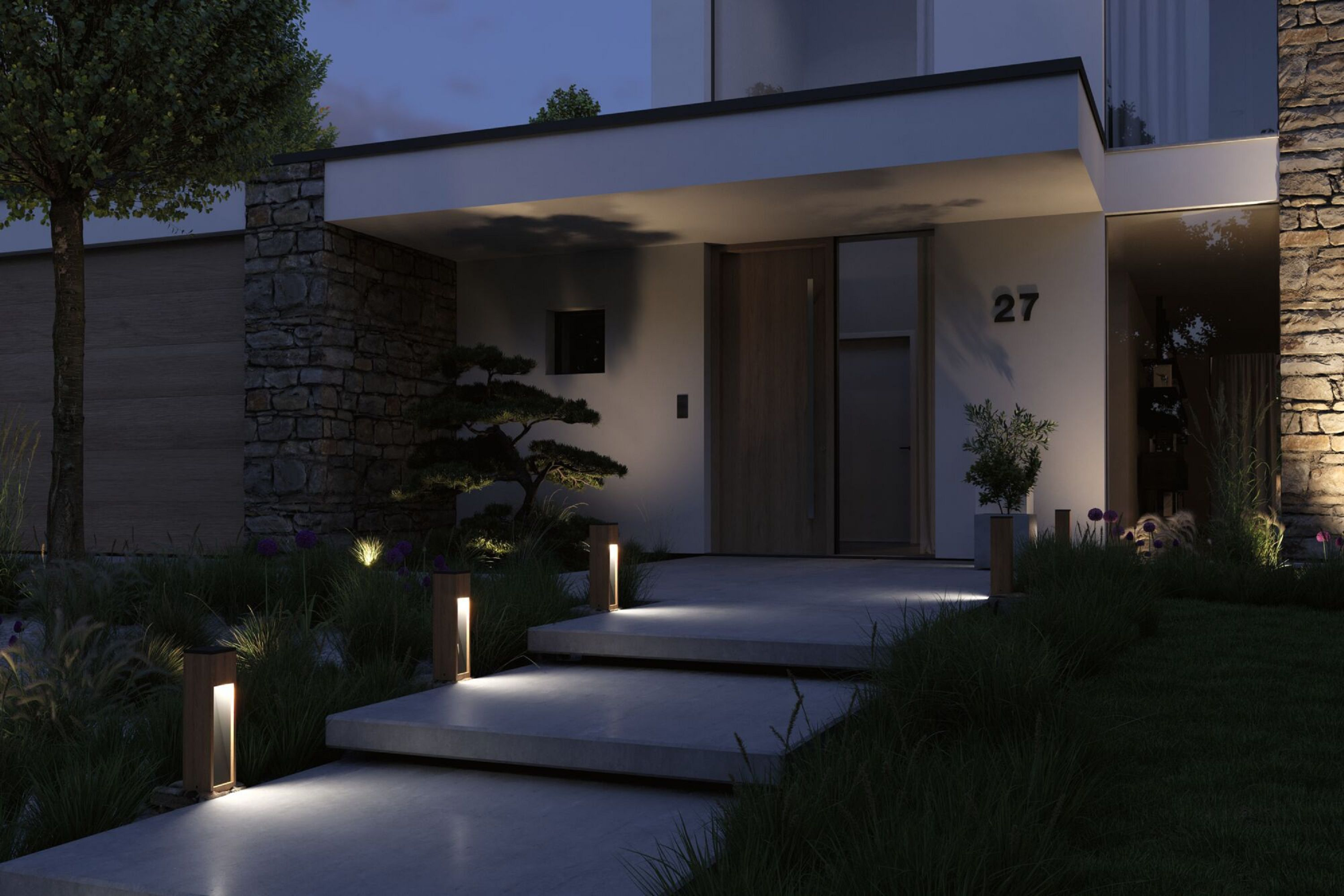 Nowoczesne wejście do domu w nocy. Oświetlona ścieżka prowadzi do drewnianych drzwi. Kamienny mur i oświetlone rośliny.