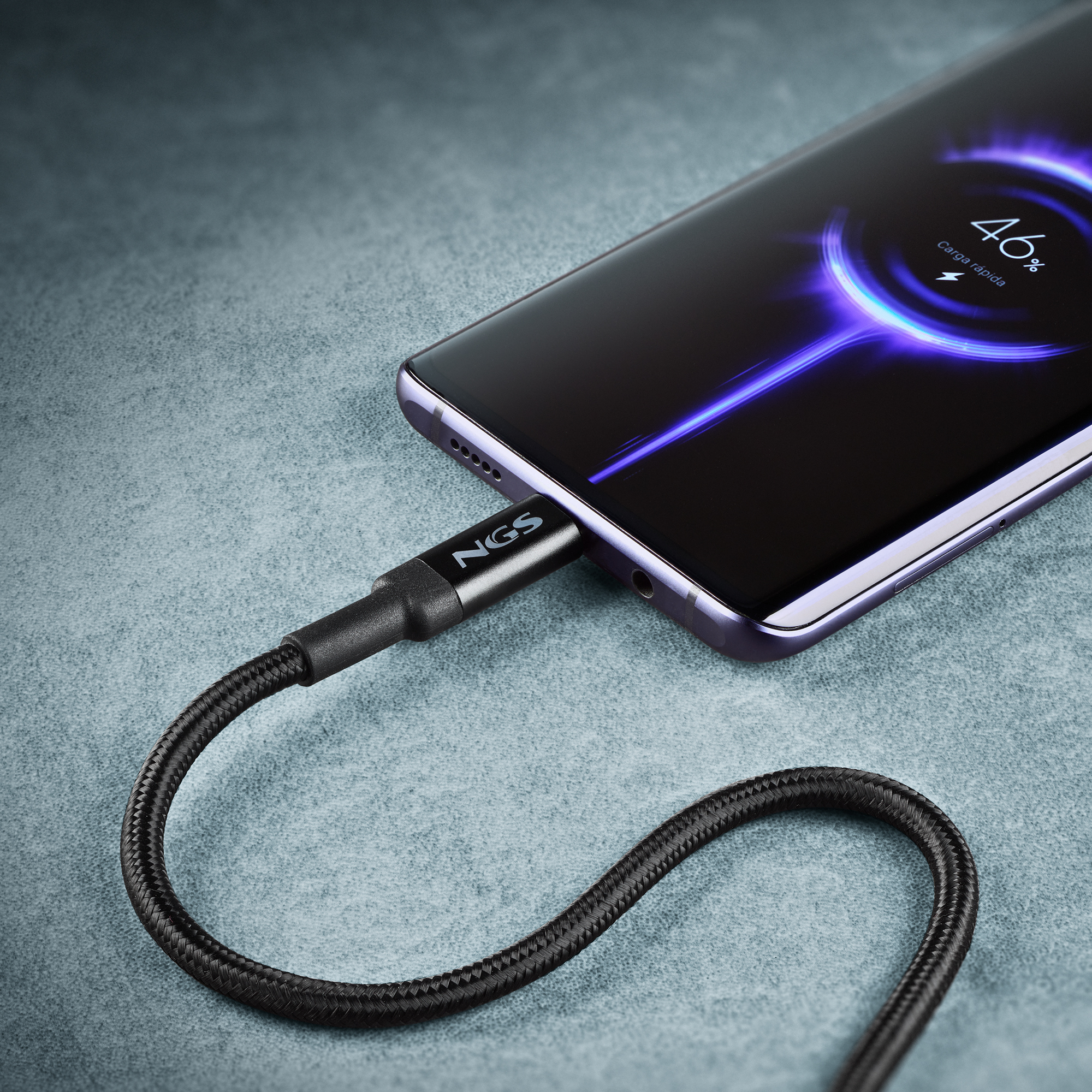 Un teléfono cargando con un cable negro. La pantalla muestra el 46% de carga. El cable está conectado al teléfono.
