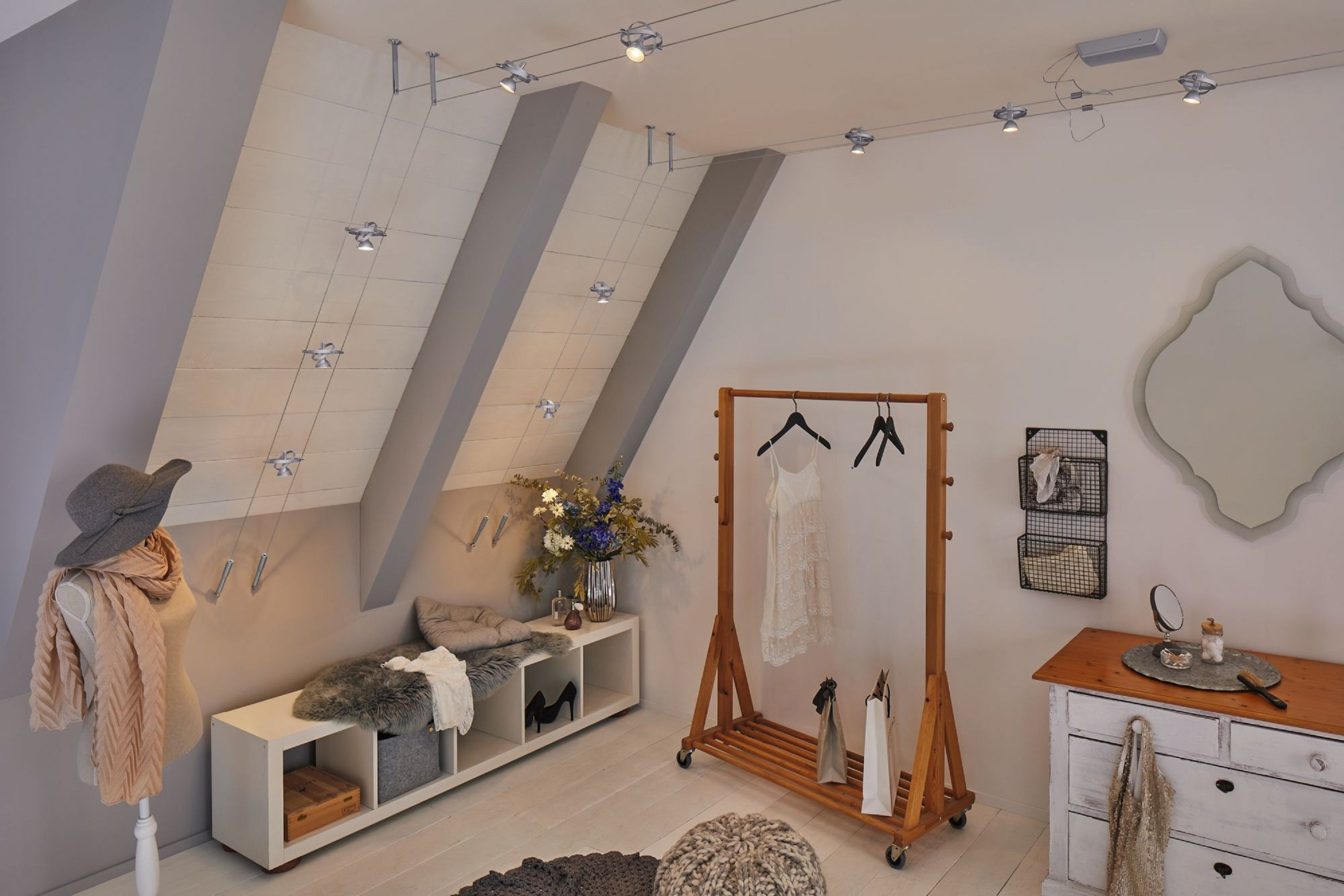 Una stanza con soffitto spiovente, illuminazione a binario, attaccapanni, specchio e manichino. La stanza è decorata in toni neutri.