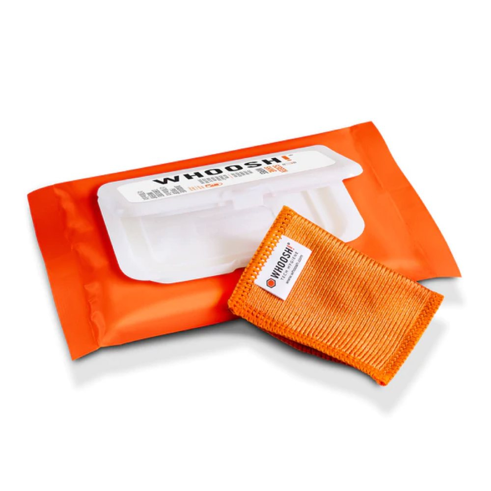 Orangene Packung mit weißem Deckel. Orangefarbenes Mikrofasertuch liegt neben der Packung. Weißer Hintergrund.