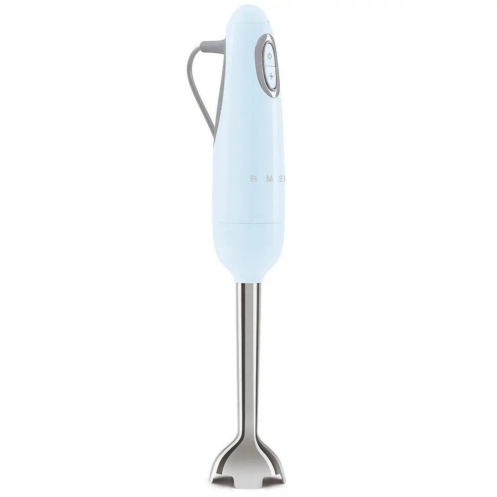 Un frullatore a immersione Smeg azzurro chiaro su sfondo bianco. Ha una lama argentata e pulsanti di controllo.