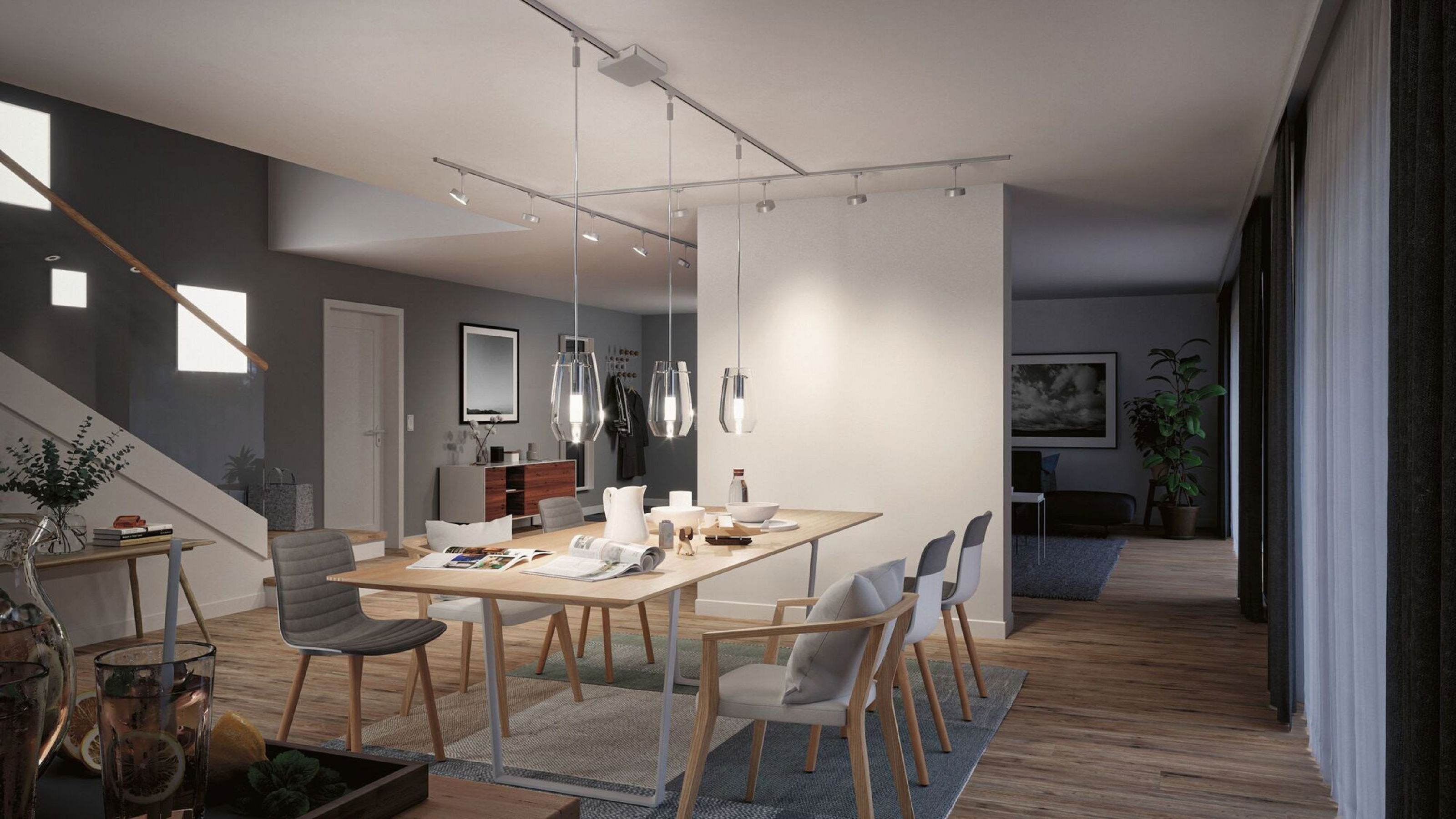Modernes Esszimmer mit Holztisch, Stühlen und Pendelleuchten. Eine Treppe und eine offene Tür sind ebenfalls zu sehen.