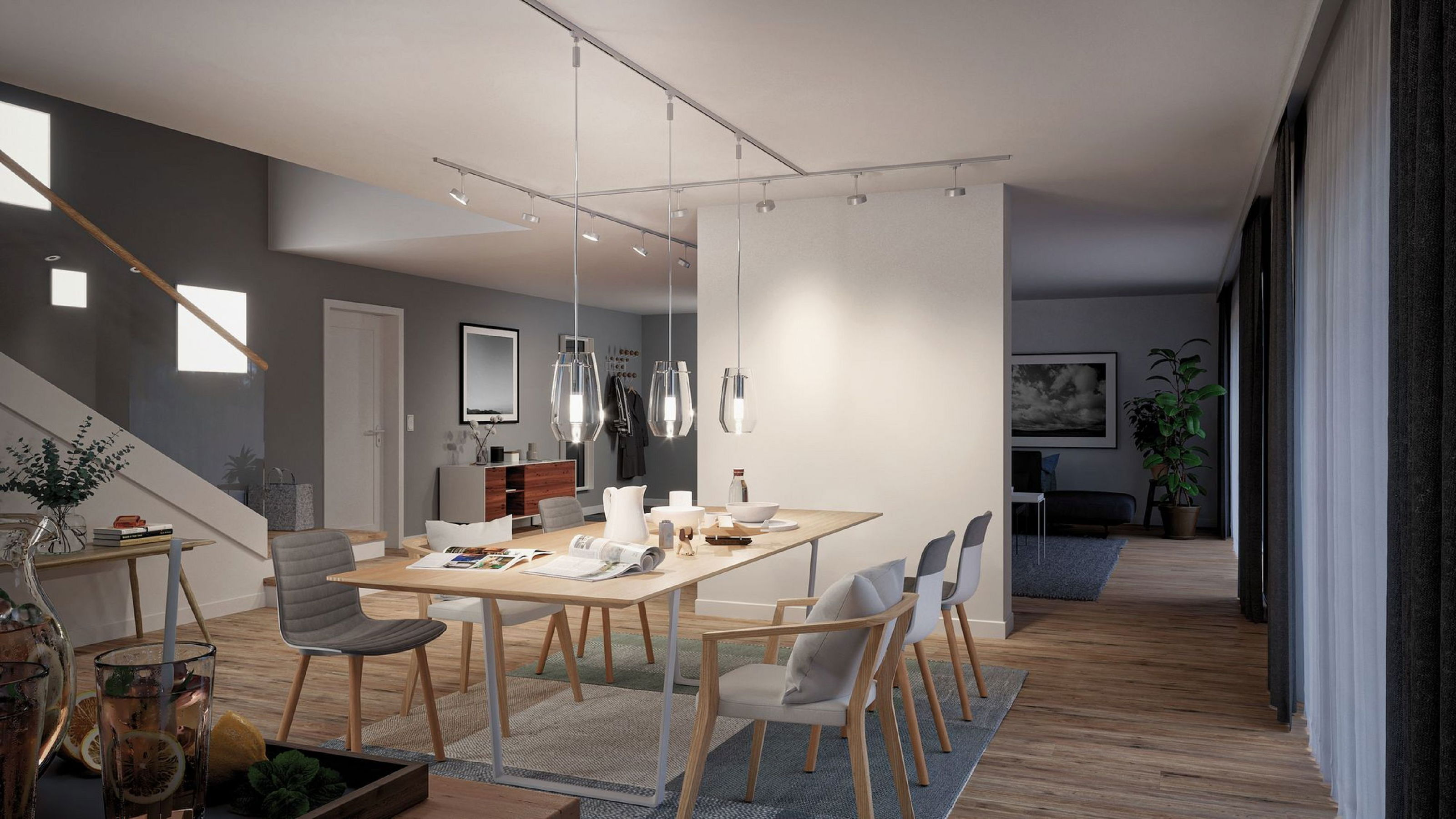 Ein modernes Esszimmer mit Holztisch, Stühlen und Hängelampen. Im Hintergrund sind eine Treppe und ein offener Durchgang zu sehen.