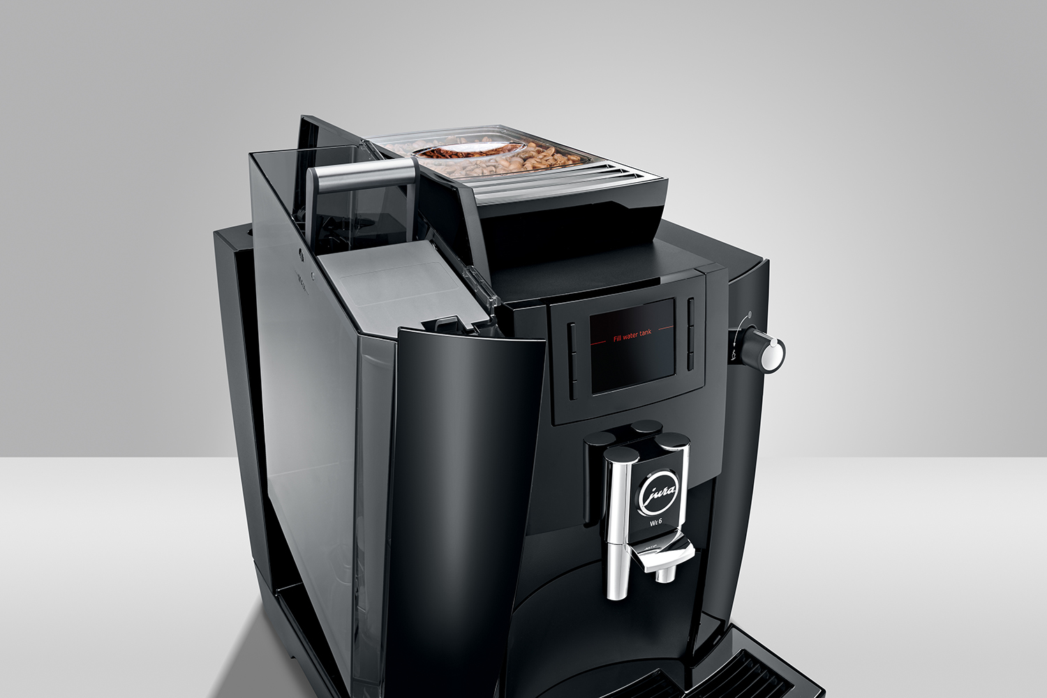 Macchina da caffè Jura nera con scomparti aperti, un contenitore per chicchi e un display digitale. La macchina è su una superficie bianca.