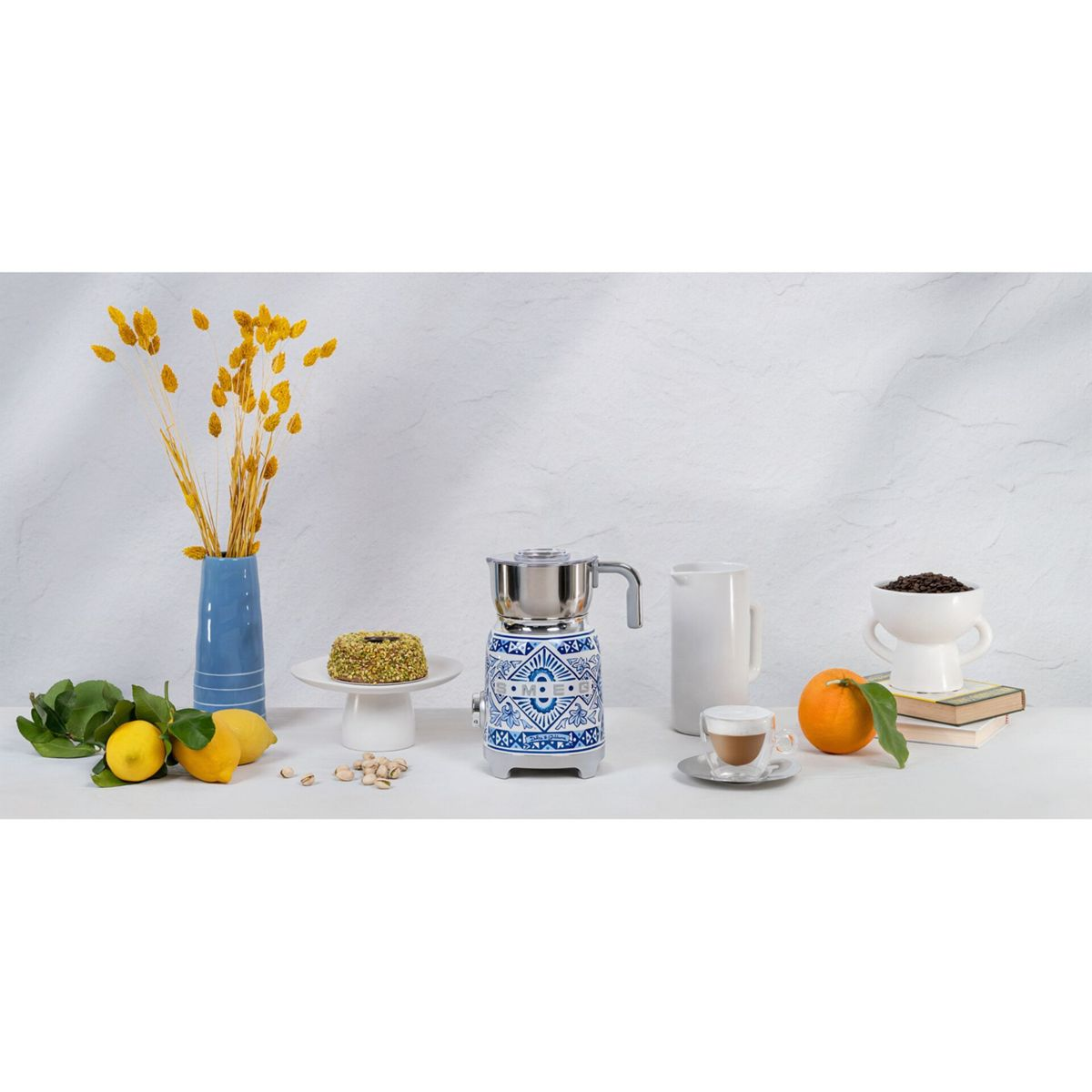 Stilleben mit Kaffeemaschine, Zitronen, Kuchen, Orange, Kaffeetasse, Vase mit gelben Blumen und Kaffeebohnen.