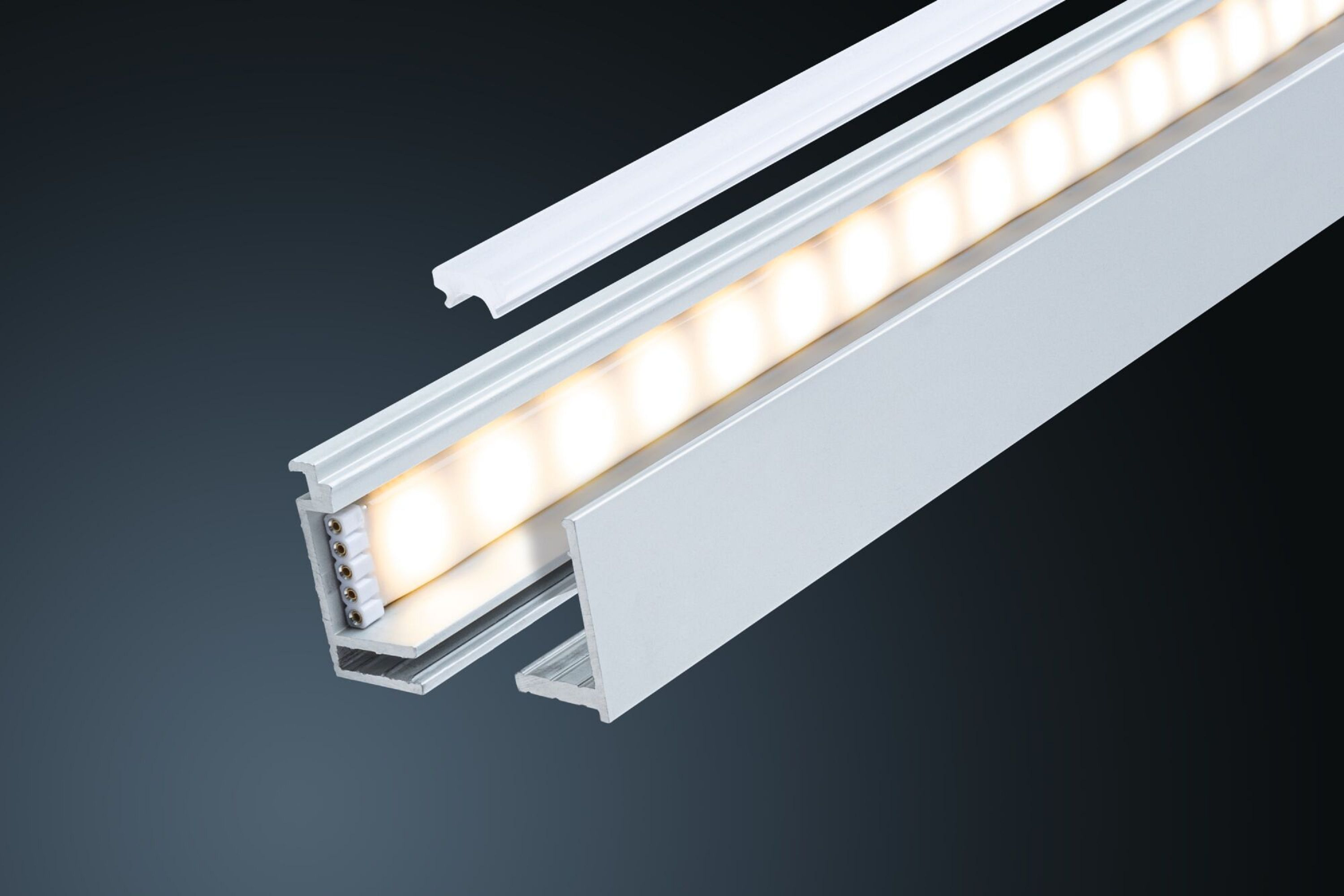 Eine lineare LED-Leuchte mit weißer Abdeckung und silberfarbenem Metallrahmen vor einem dunklen Hintergrund.