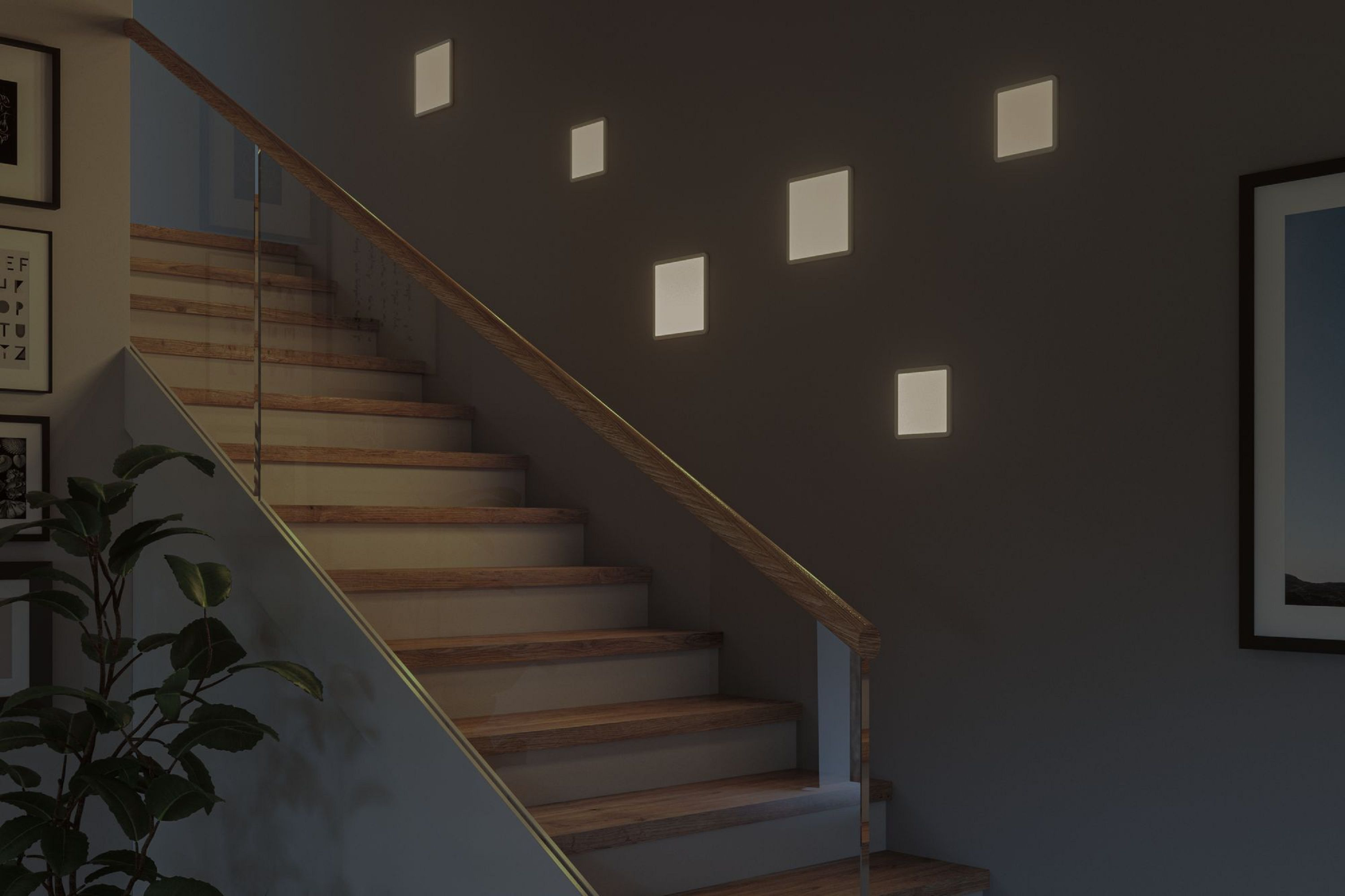 Eine Treppe mit Holzstufen und einem Glasgeländer. An der Wand befinden sich beleuchtete quadratische Lichter.