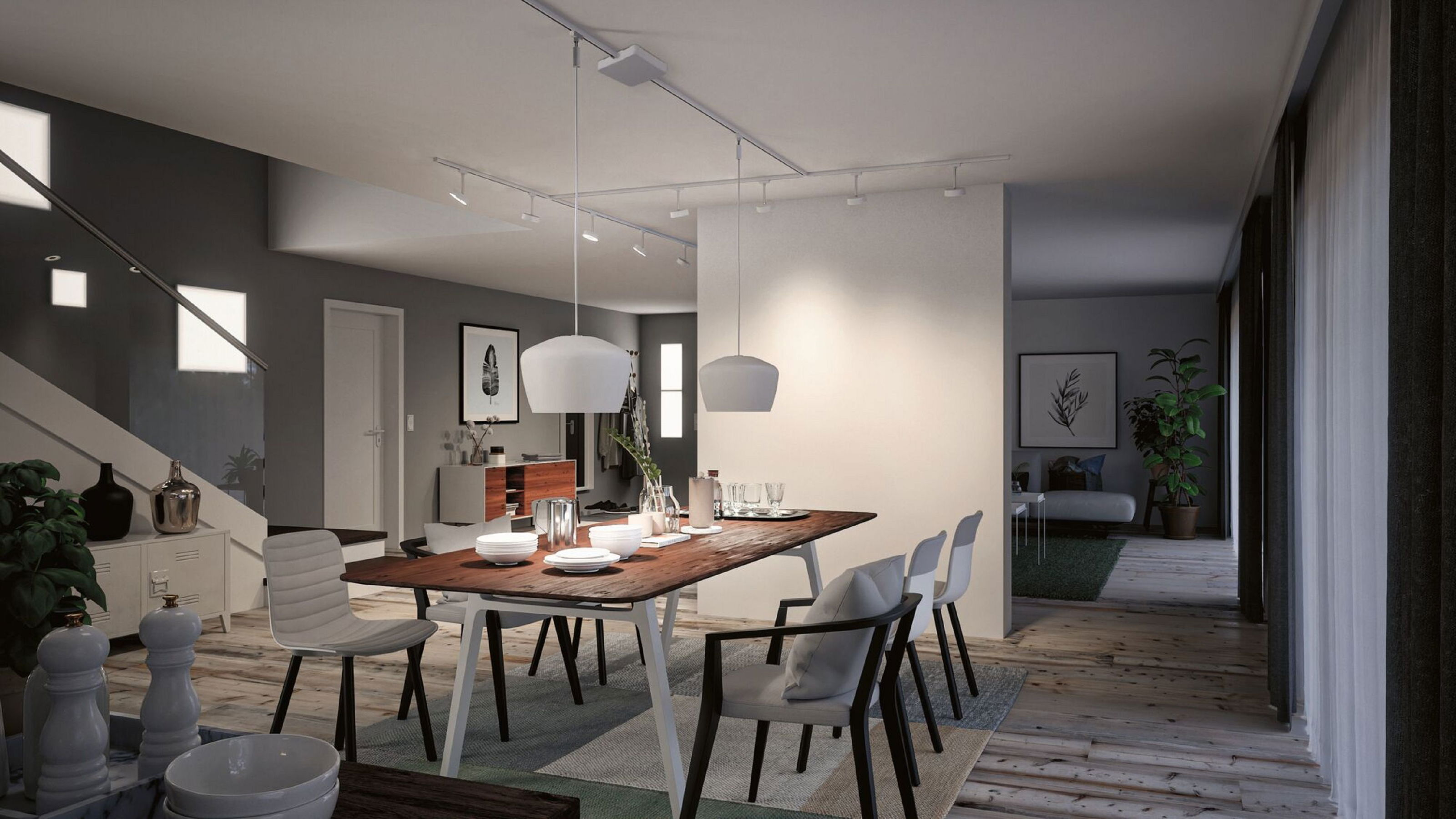 Esszimmer mit Holztisch, weißen Stühlen und Pendelleuchten. Blick in ein Wohnzimmer und Treppe links.