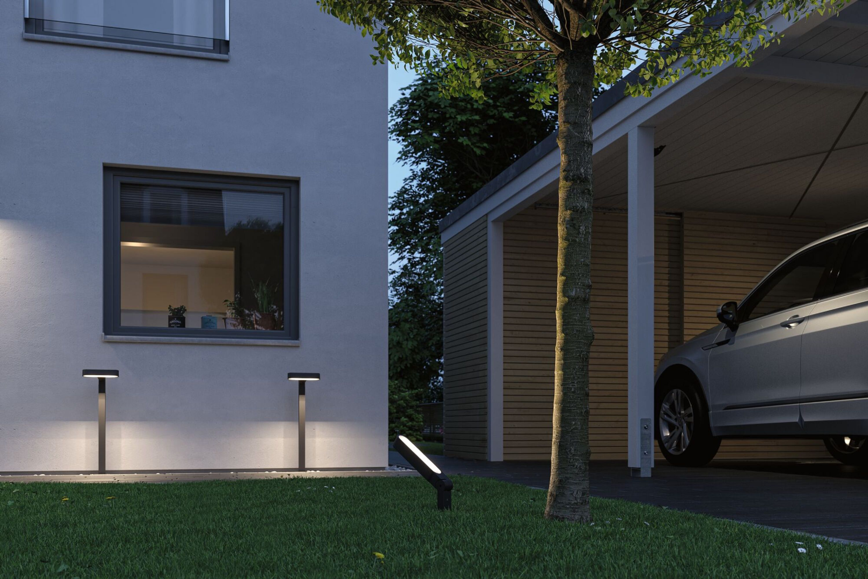 Ein Haus mit Carport. Ein Auto steht im Hafen. Gras und ein Baum stehen davor.