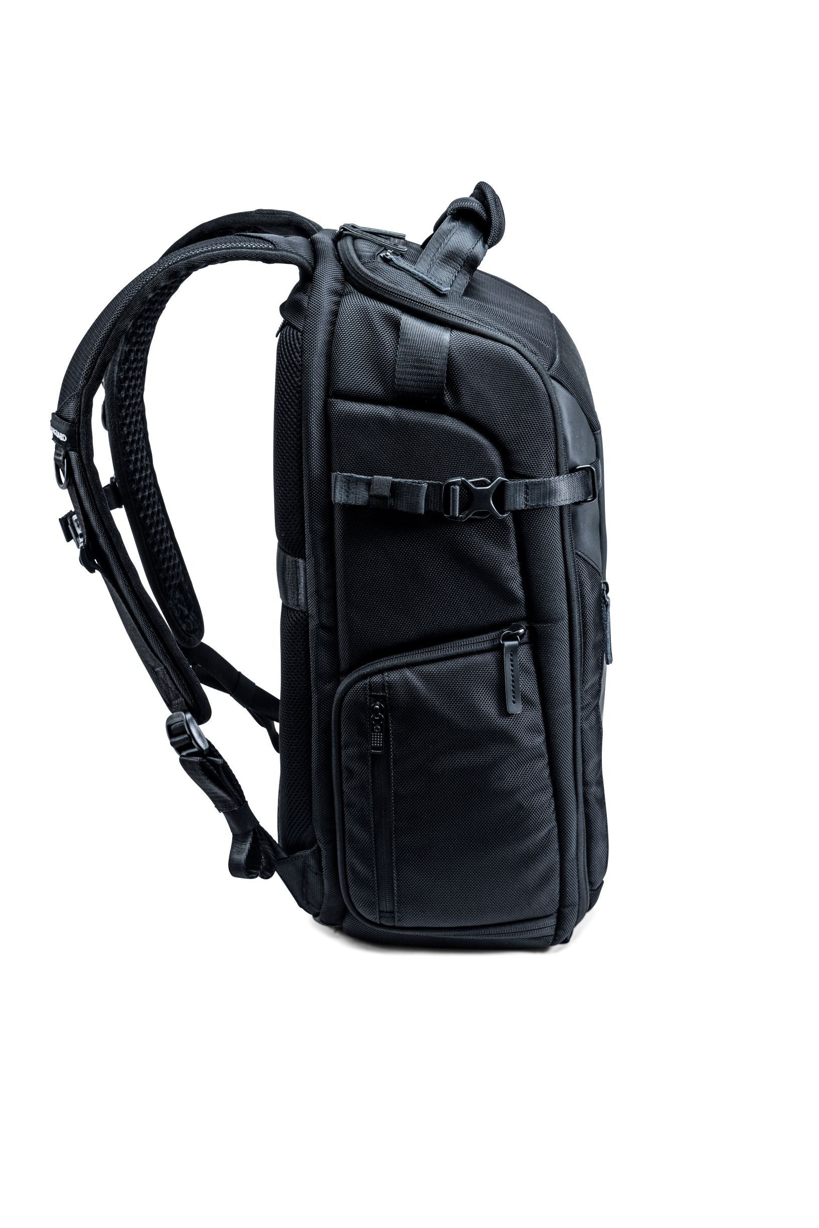 Schwarzer Rucksack, Seitenansicht, vor weißem Hintergrund. Gurte, Reißverschlüsse und Schnallen sind sichtbar. Das Material ist strukturiert.