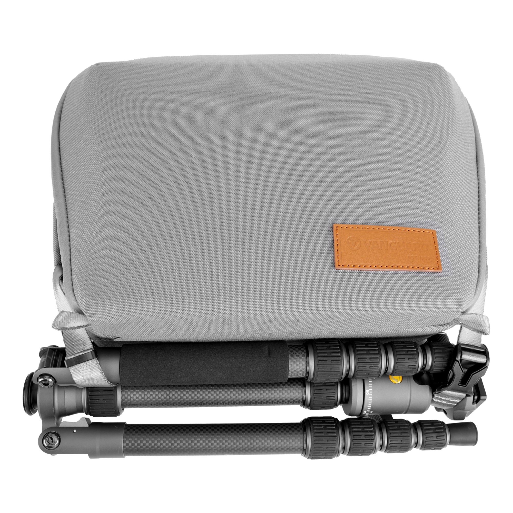 Eine graue Stativtasche liegt auf einem zusammengeklappten Stativ. Die Tasche hat einen Lederaufnäher mit Logo. Der Hintergrund ist weiß.