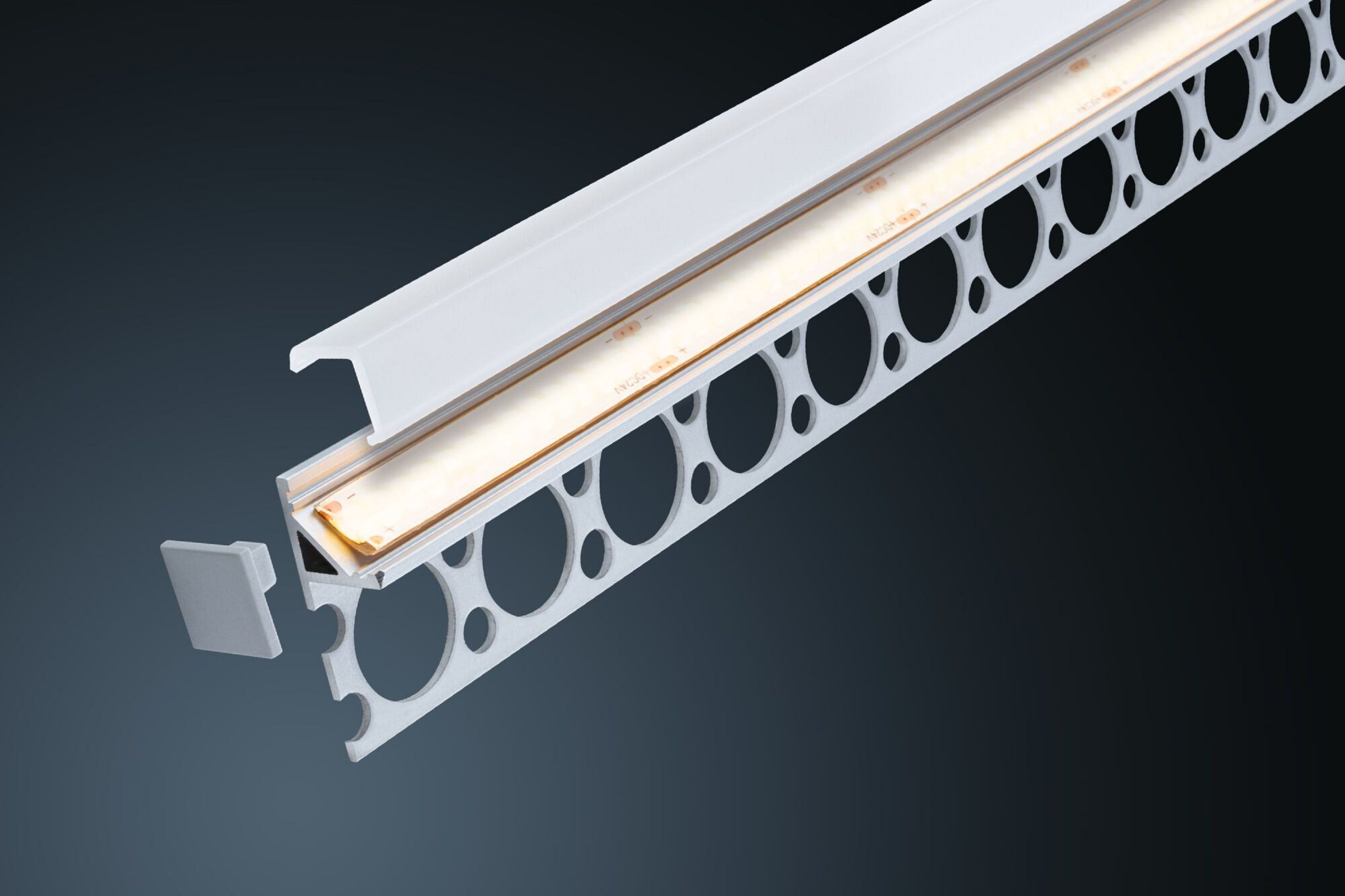 Weißes LED-Streifenprofil. Es hat eine perforierte Seite und eine Abdeckung. Ein abgetrenntes Teil ist links.
