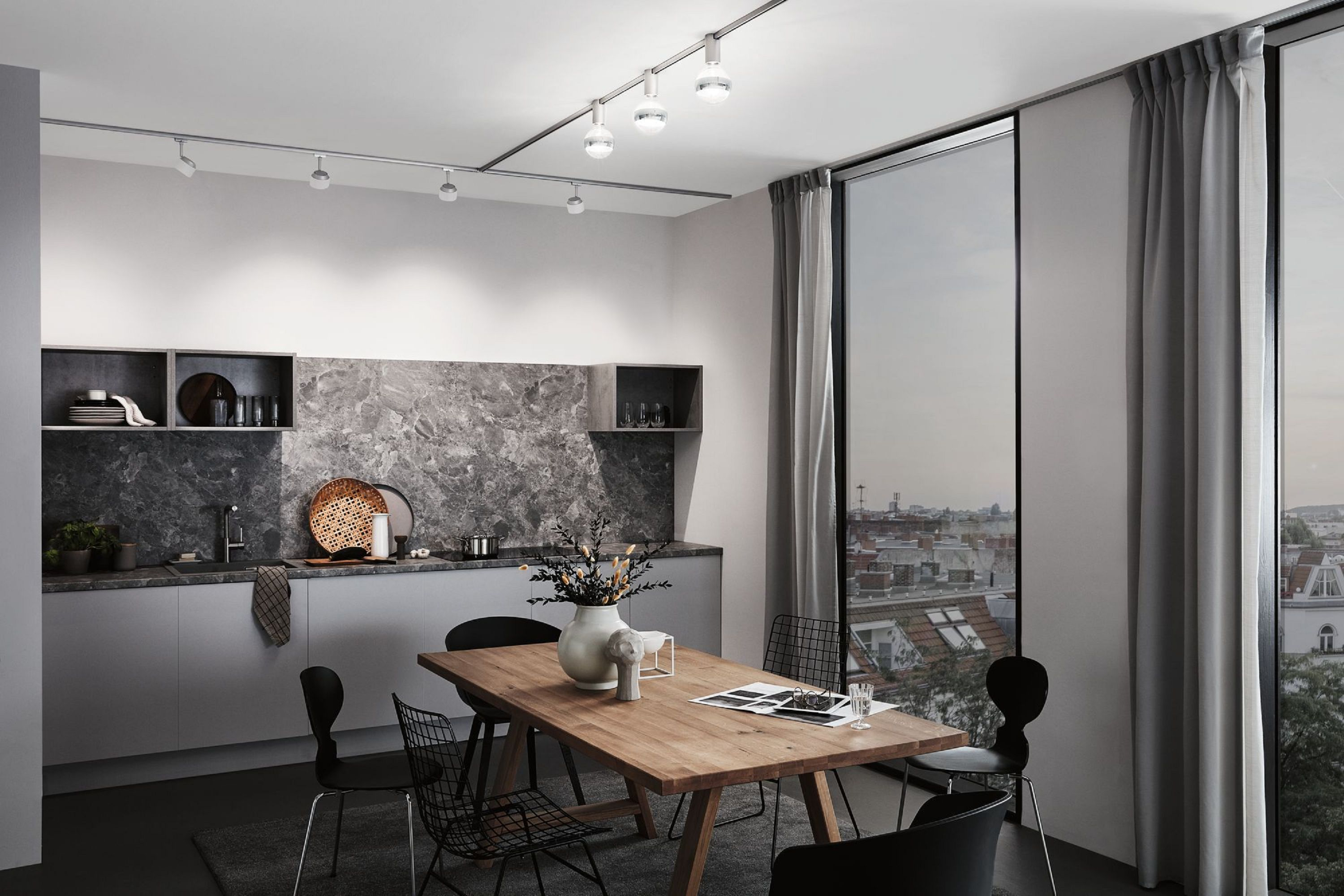Eine moderne Küche mit Essbereich. Ein großes Fenster zeigt einen Blick auf die Stadt. Es gibt einen Holztisch und schwarze Stühle.