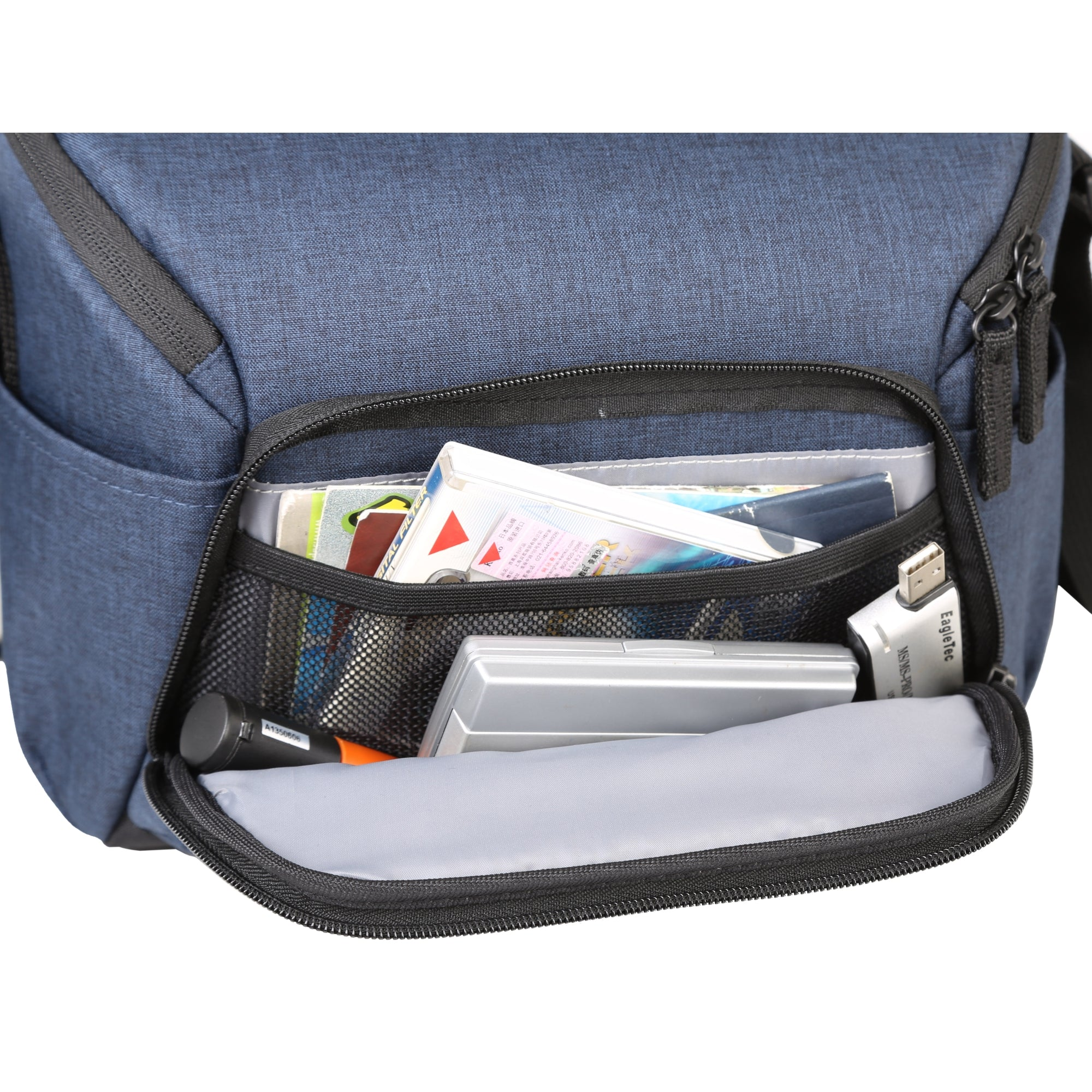Bolsa azul con bolsillo abierto con compartimento de malla. Dentro: documentos, una unidad USB y otros elementos.