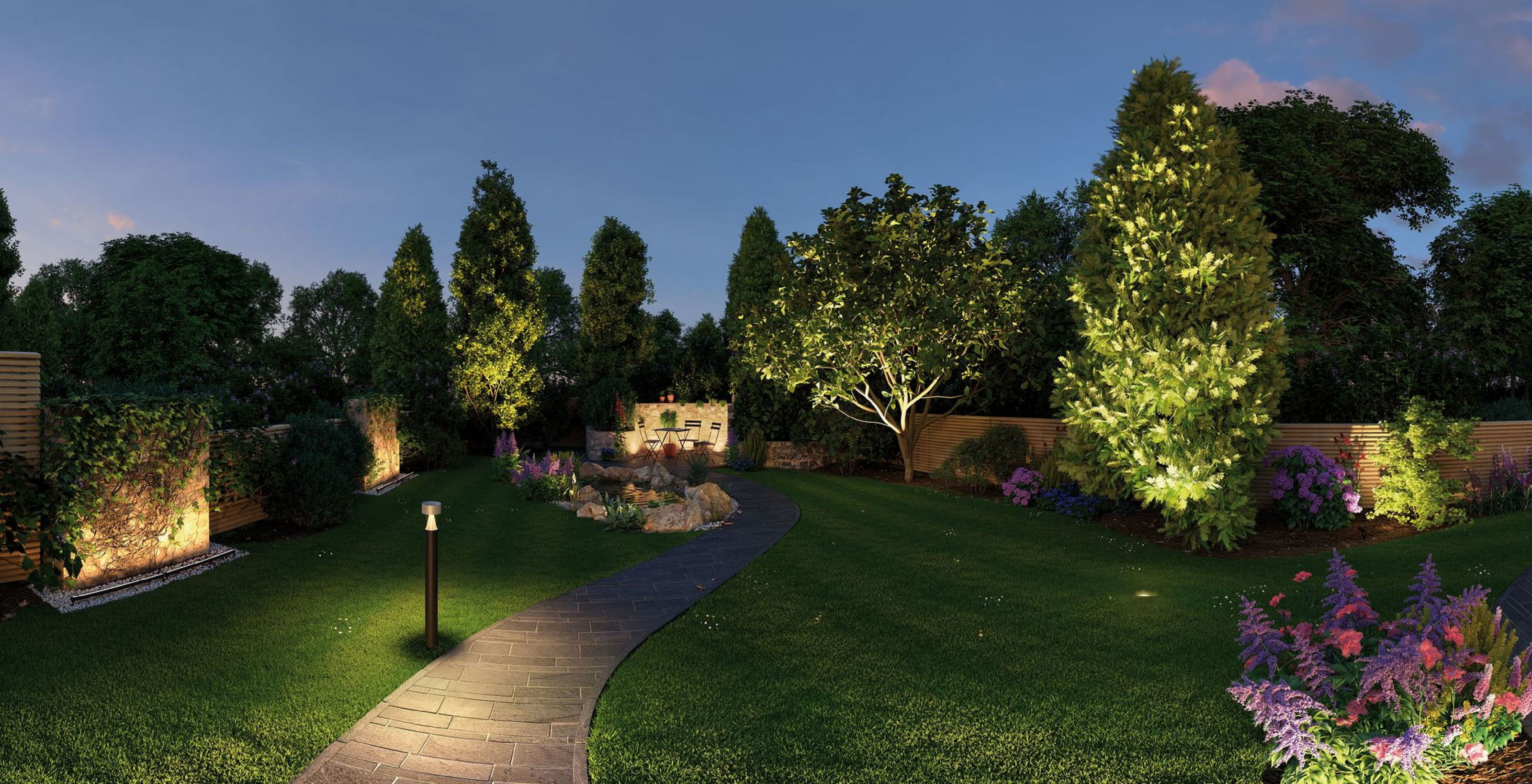 Ein beleuchteter Gartenweg schlängelt sich durch einen Rasen. Bäume und Blumen sind mit Scheinwerfern beleuchtet. Ein Teich und Sitzgelegenheiten sind im Hintergrund.