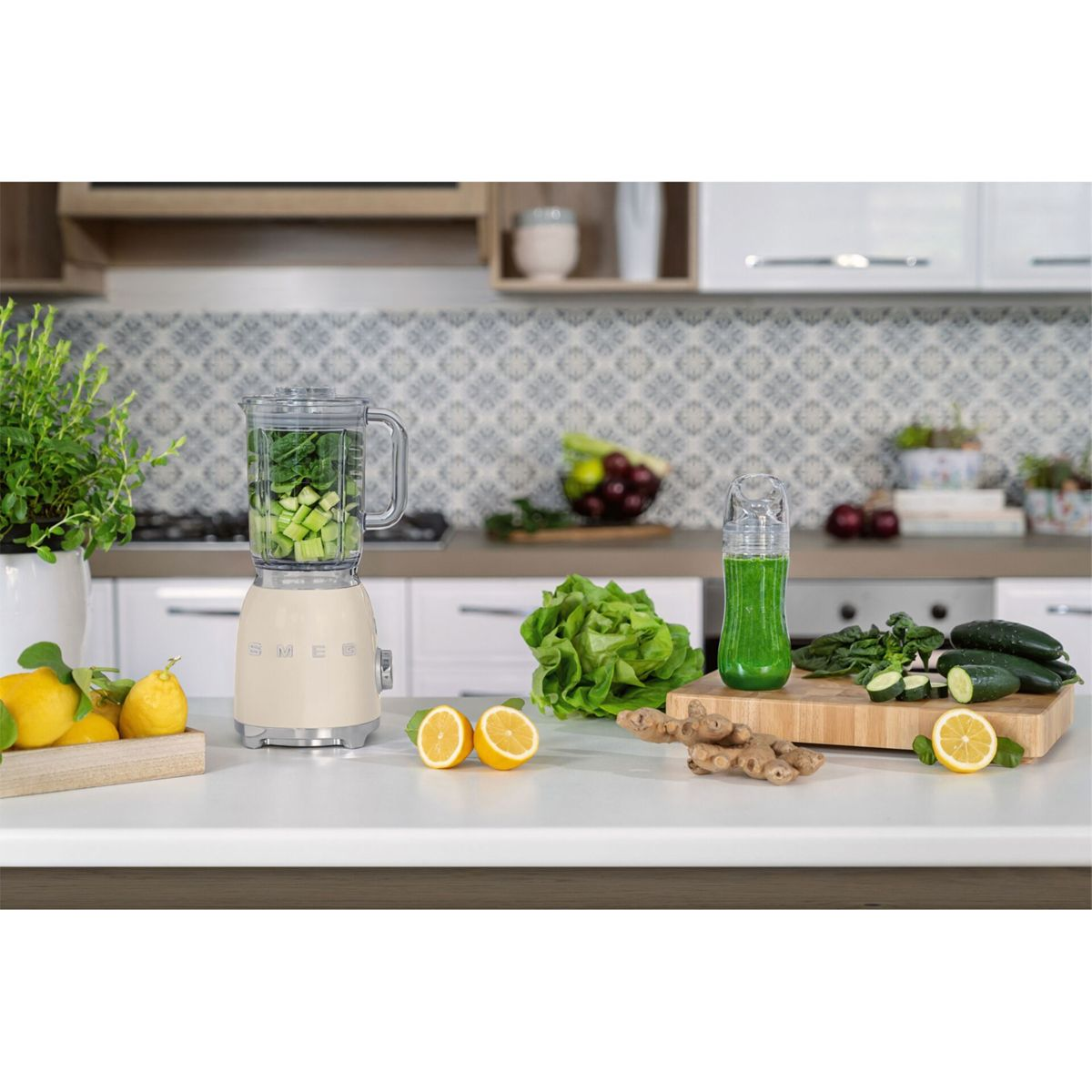 Scena kuchenna z blenderem, owocami i warzywami. Koktajl znajduje się w butelce. Cytryny, imbir i ogórki leżą na blacie.