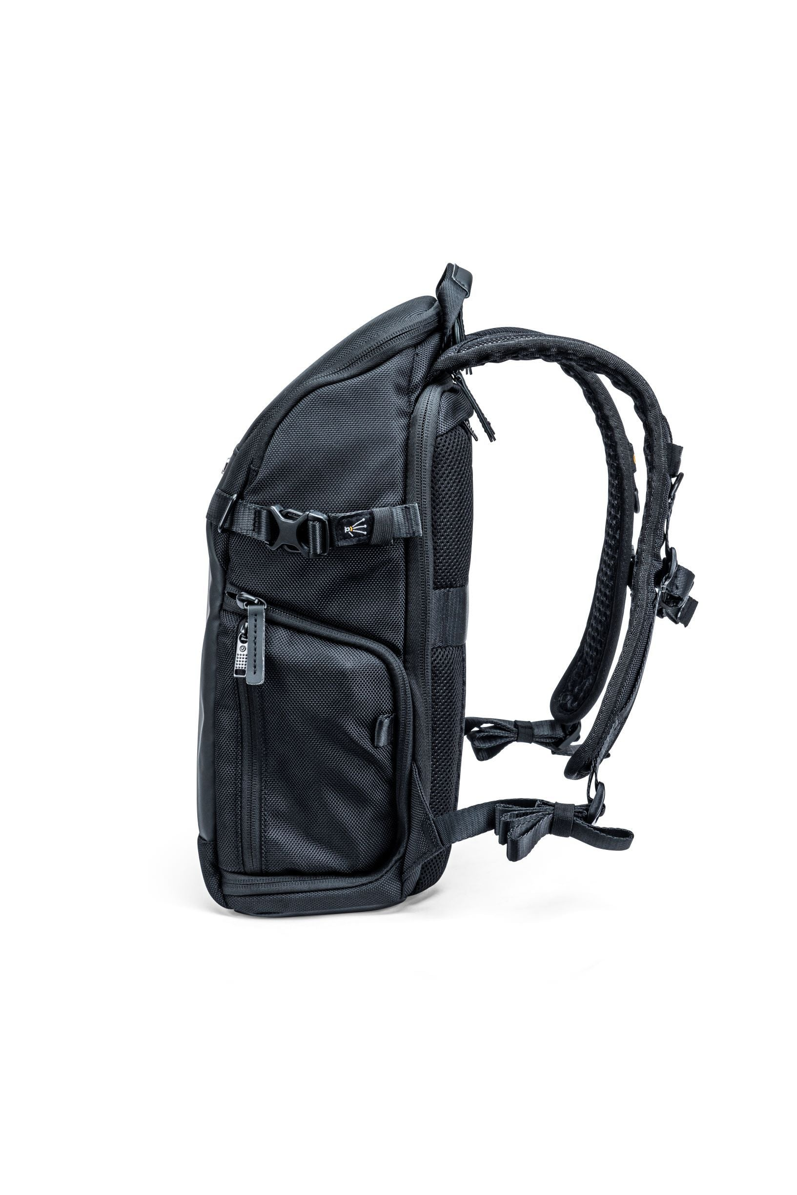 Mochila negra sobre fondo blanco. Características: correas, hebillas, cremalleras y malla. Vista lateral.