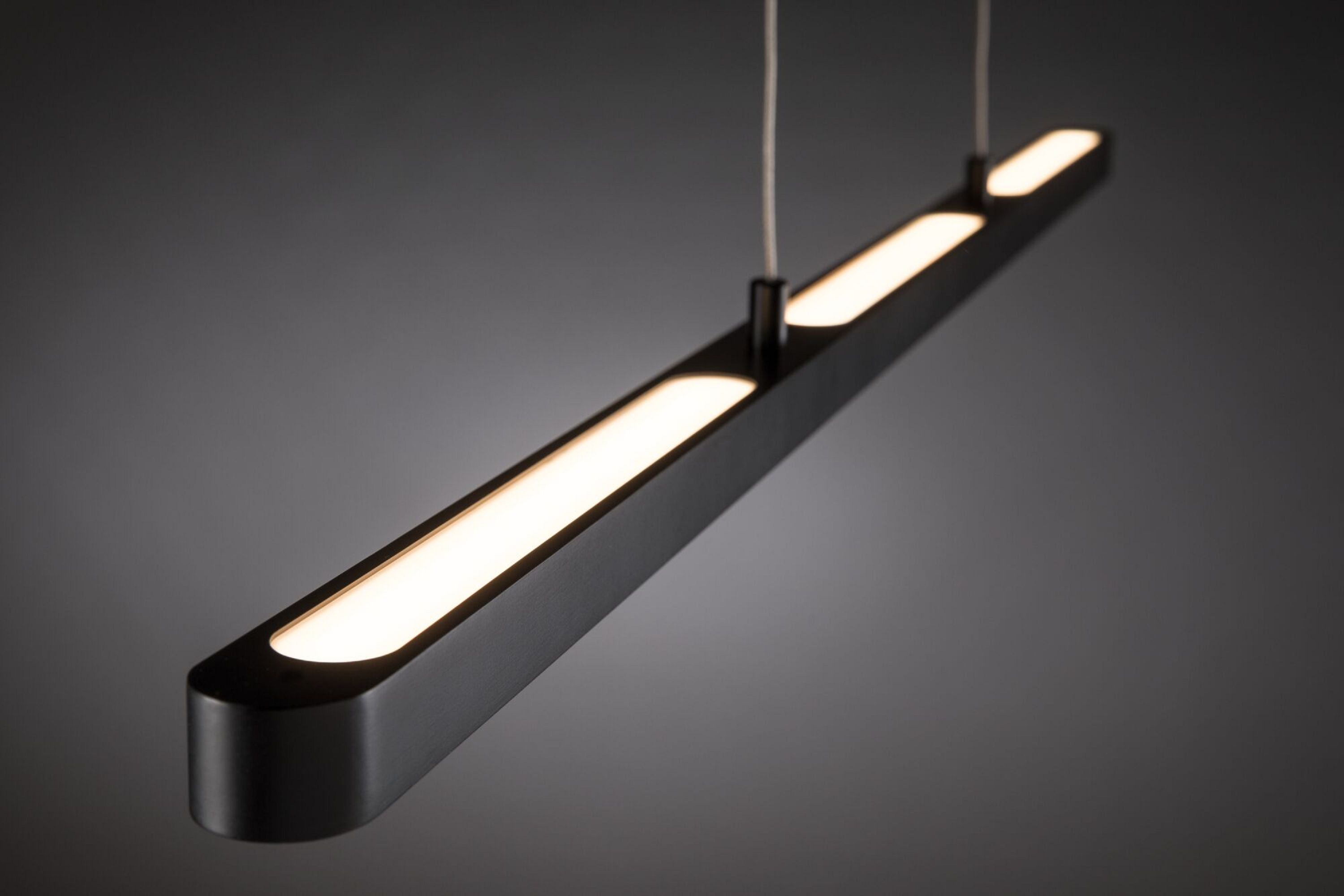 Czarna, prostokątna lampa wisząca z jasnym, białym oświetleniem na szarym tle.