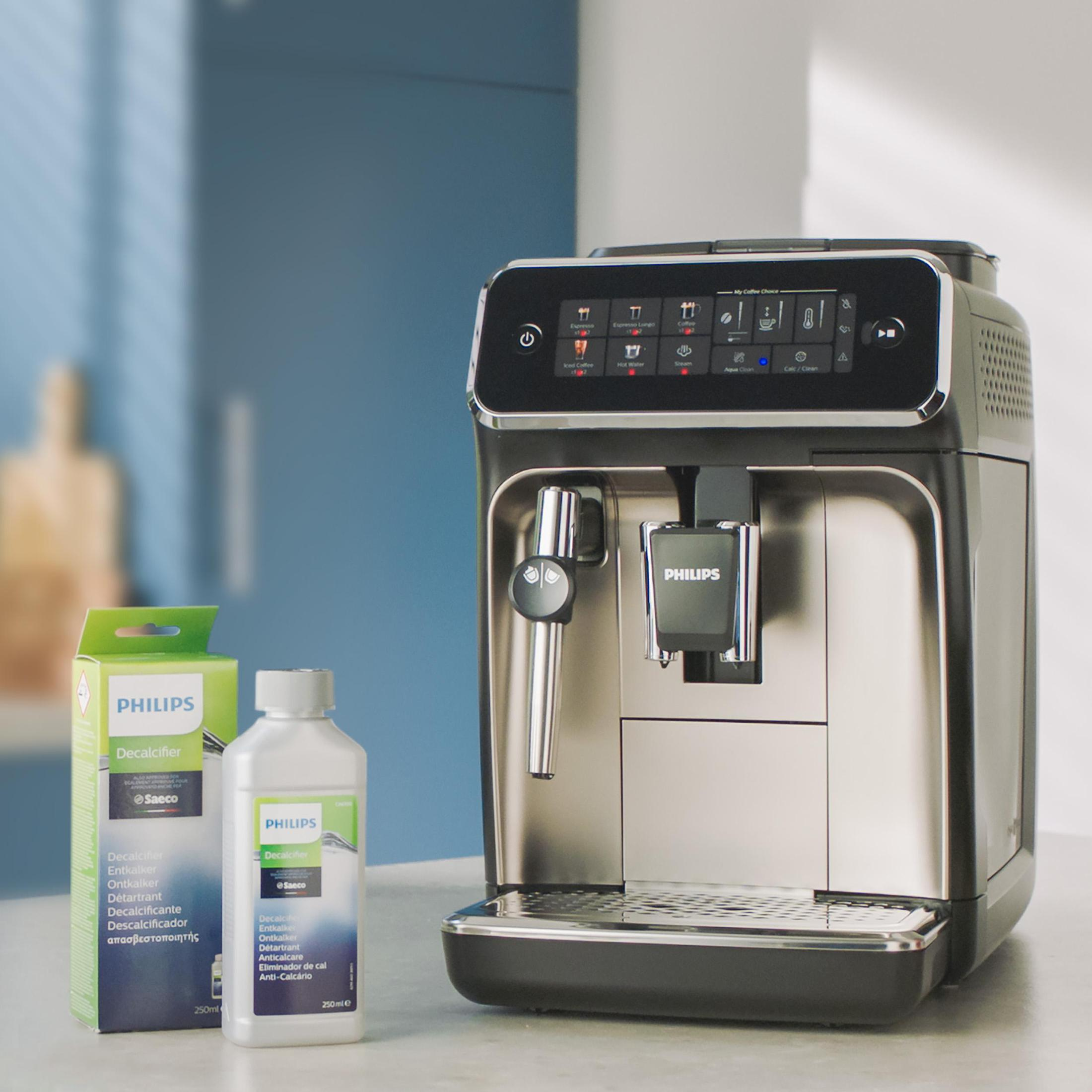 Eine Philips Espressomaschine mit Entkalkungslösung. Kartons und Flaschen stehen davor. Im Hintergrund ist eine blaue Wand.