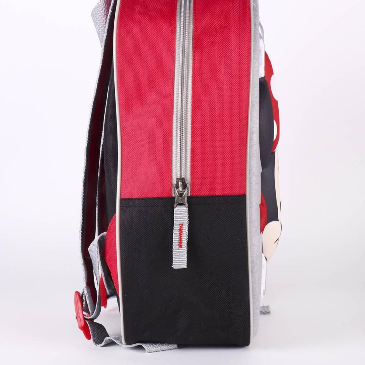 Una mochila roja, negra y gris con cremallera. Tiene correas y un diseño con un personaje de dibujos animados en el lateral.