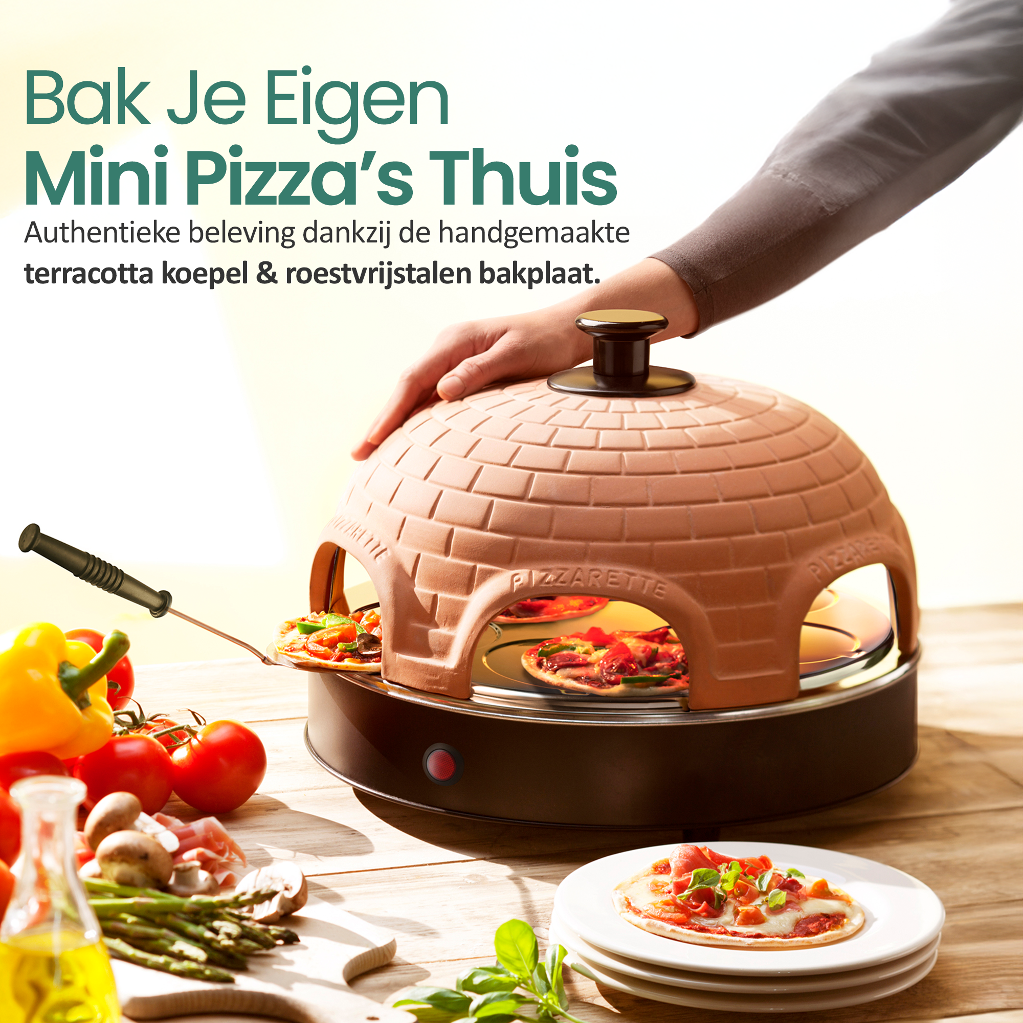 Mini-Pizzaofen mit Terrakotta-Kuppel, Hand hält ihn. Tomaten, Pilze und Pizza auf einem Holztisch.