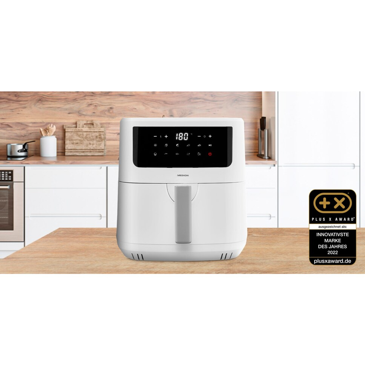 Biała frytownica na drewnianym stole w kuchni. Odznaka nagrody po prawej stronie.