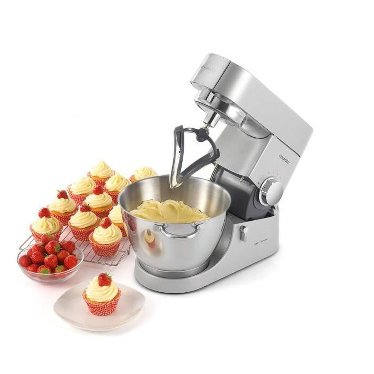 Un robot da cucina argentato con una ciotola di impasto, cupcake con fragole e una ciotola di fragole su sfondo bianco.